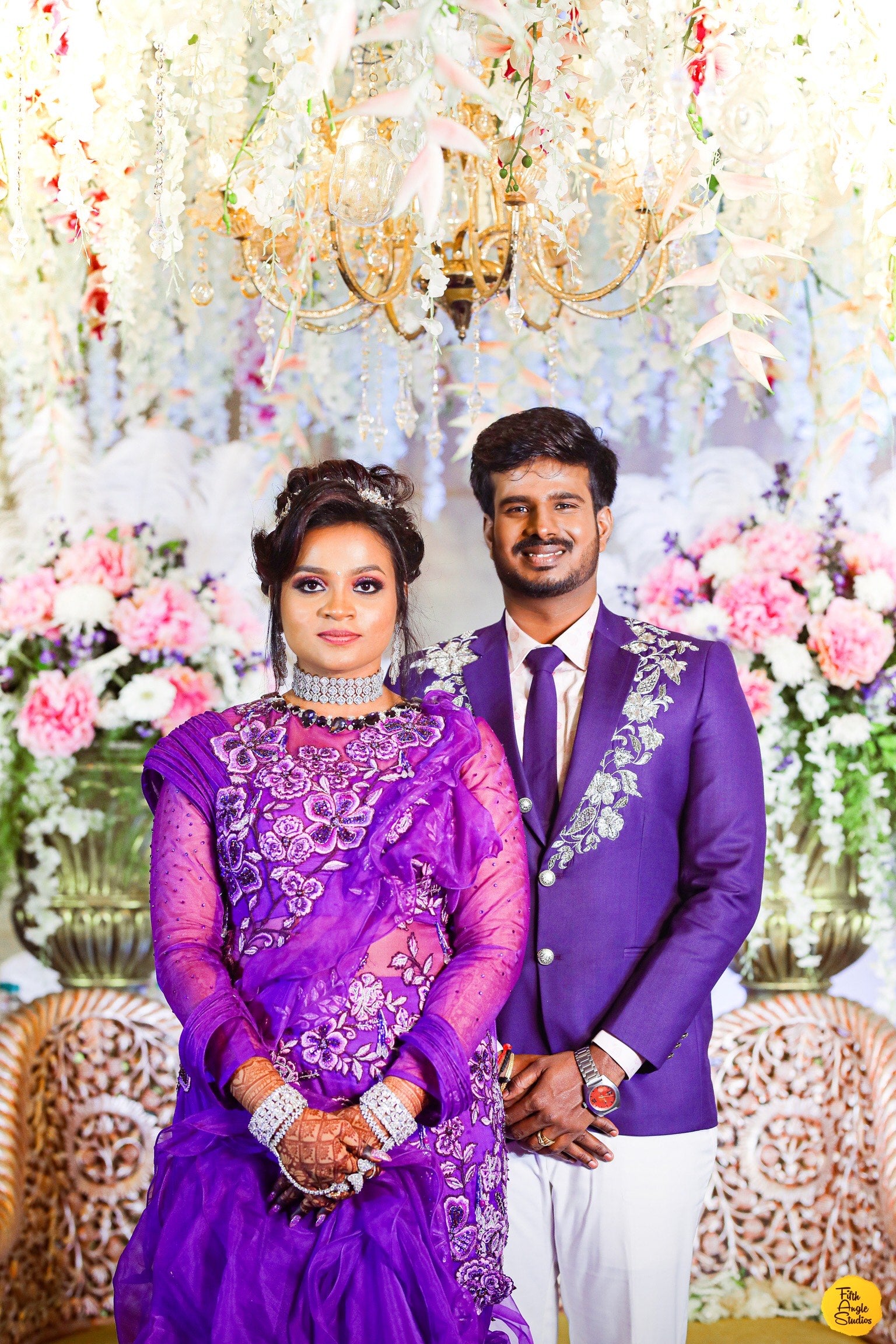 Bride Sai Sridevi & Groom posing in a purple gown and suit handcrafted by team Archana Karthick.