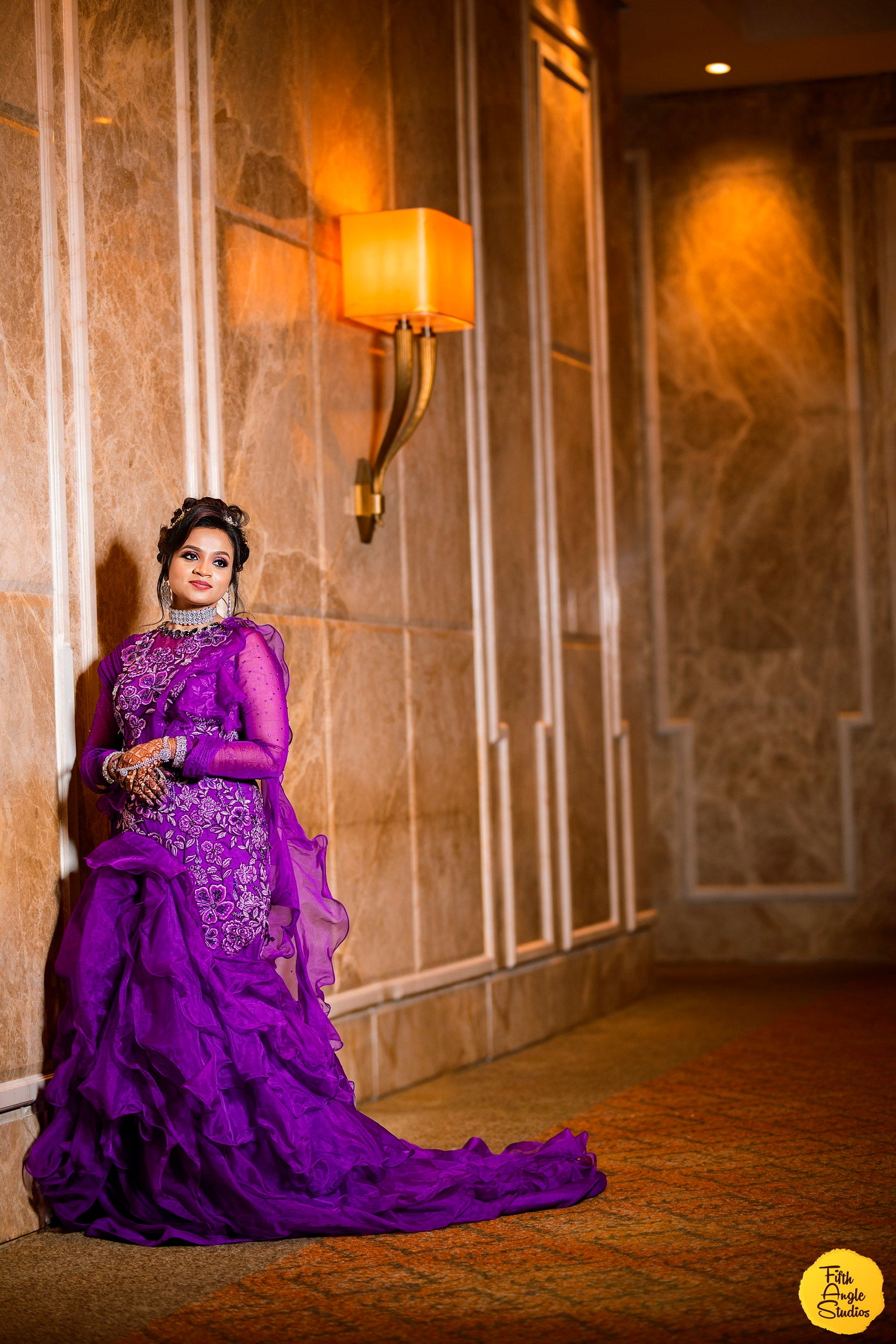 Bride Sai Sridevi posing for photo in a purple gown and suit handcrafted by team Archana Karthick.
