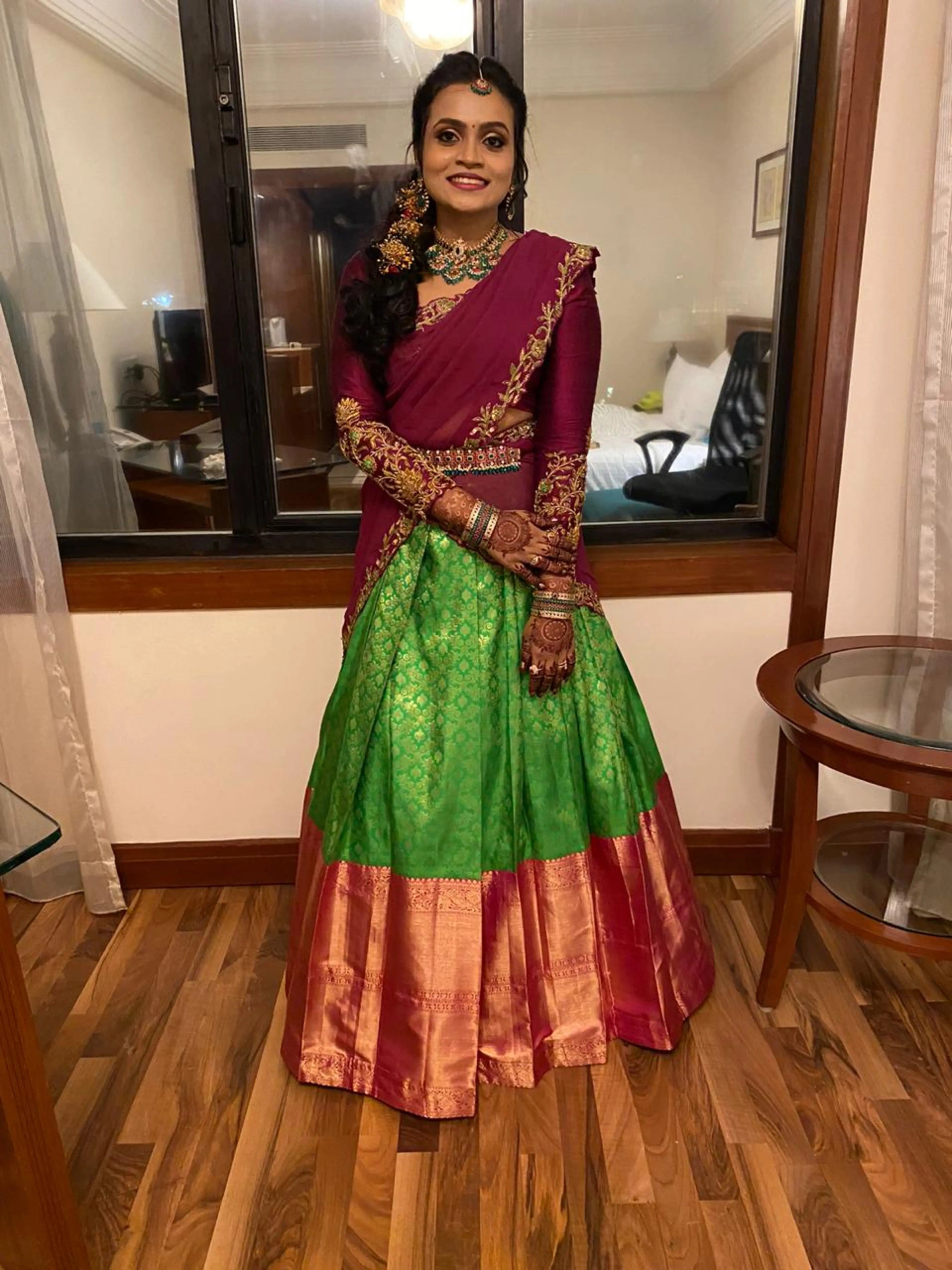 Bride Sai Sridevi posing in a magenta and green half saree, handcrafted by team Archana Karthick.
