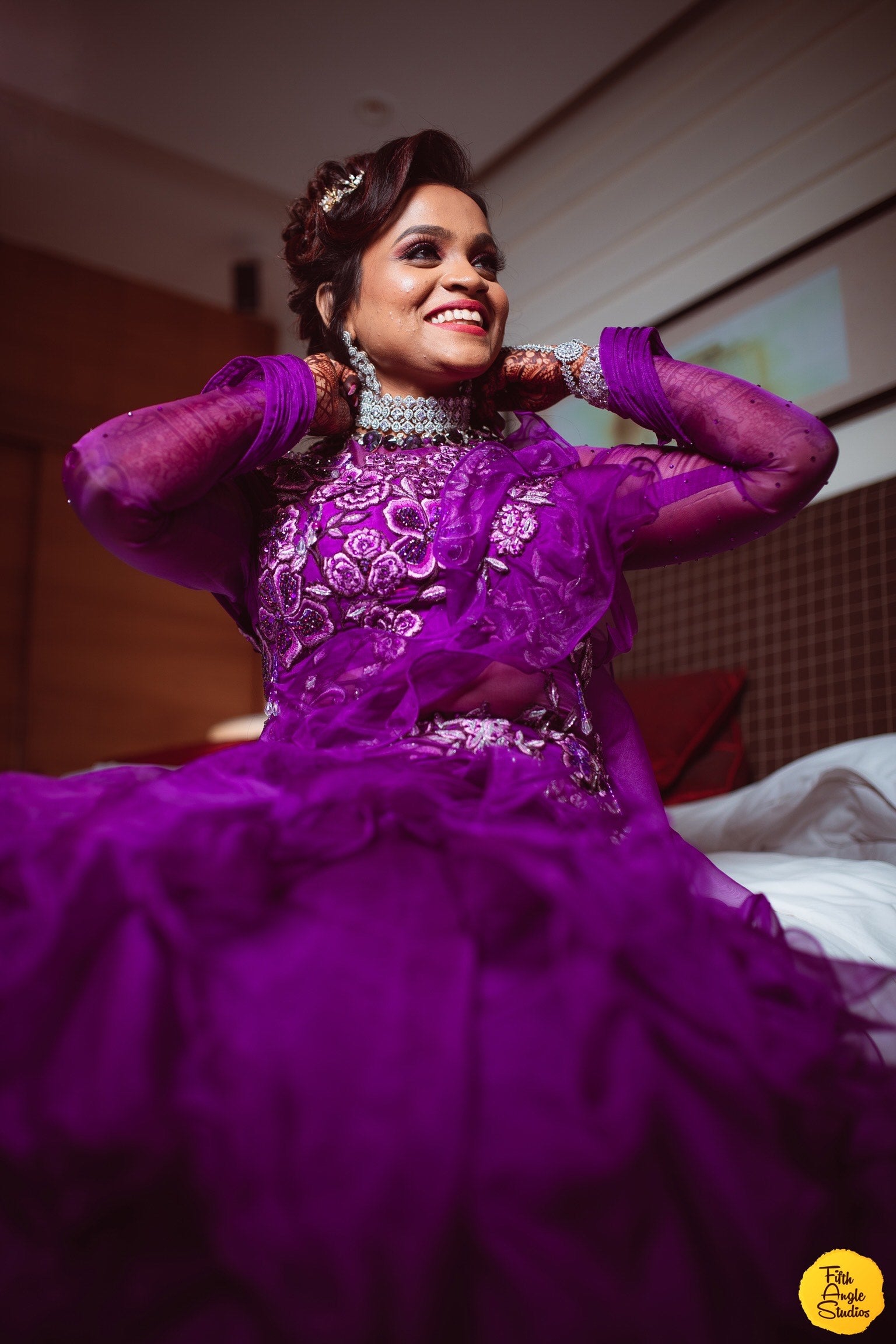 Bride Sai Sridevi posing in a purple gown and suit handcrafted by team Archana Karthick.