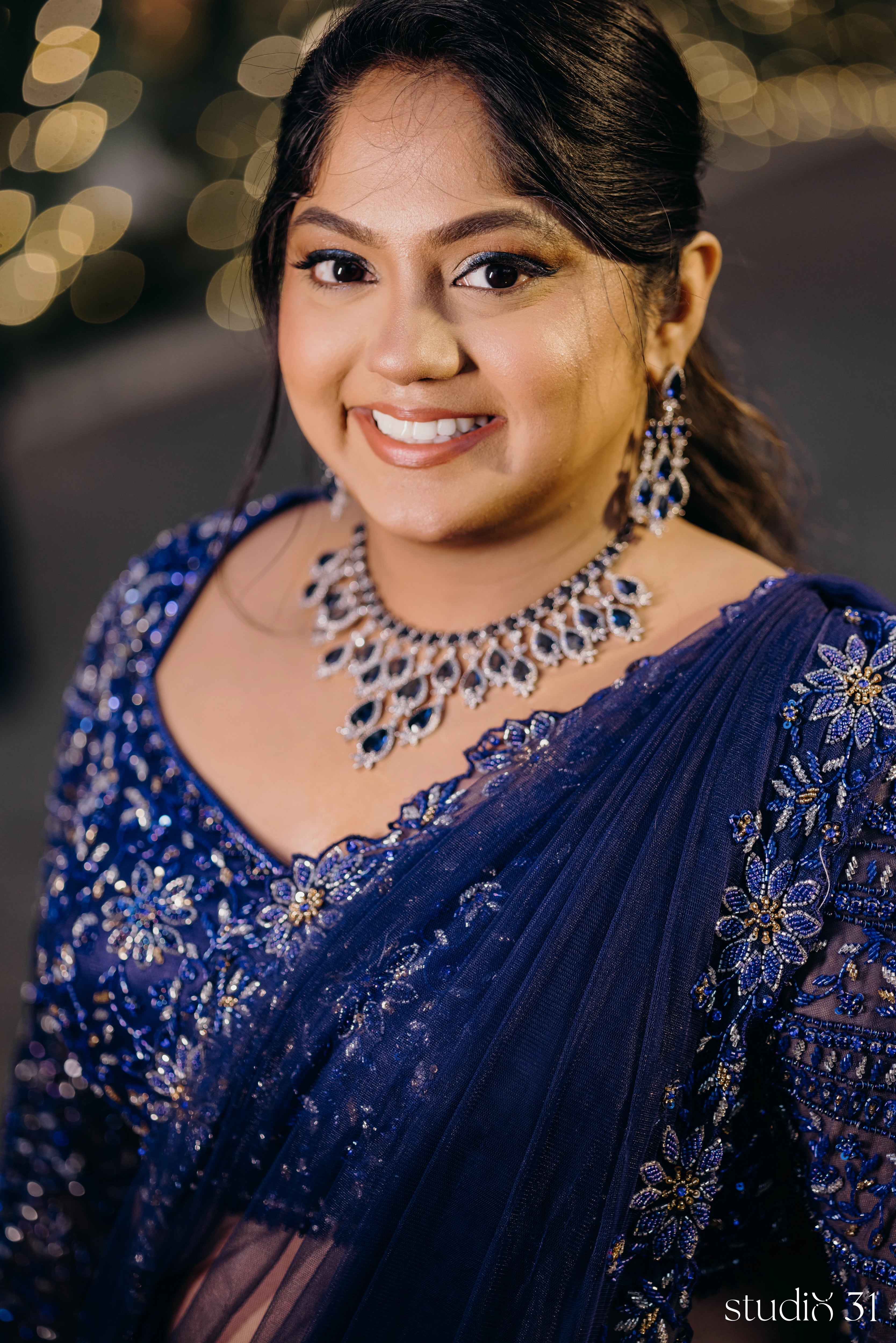 Bride Sambavi from Singapore smiles in a midnight blue lehenga by Archana Karthick