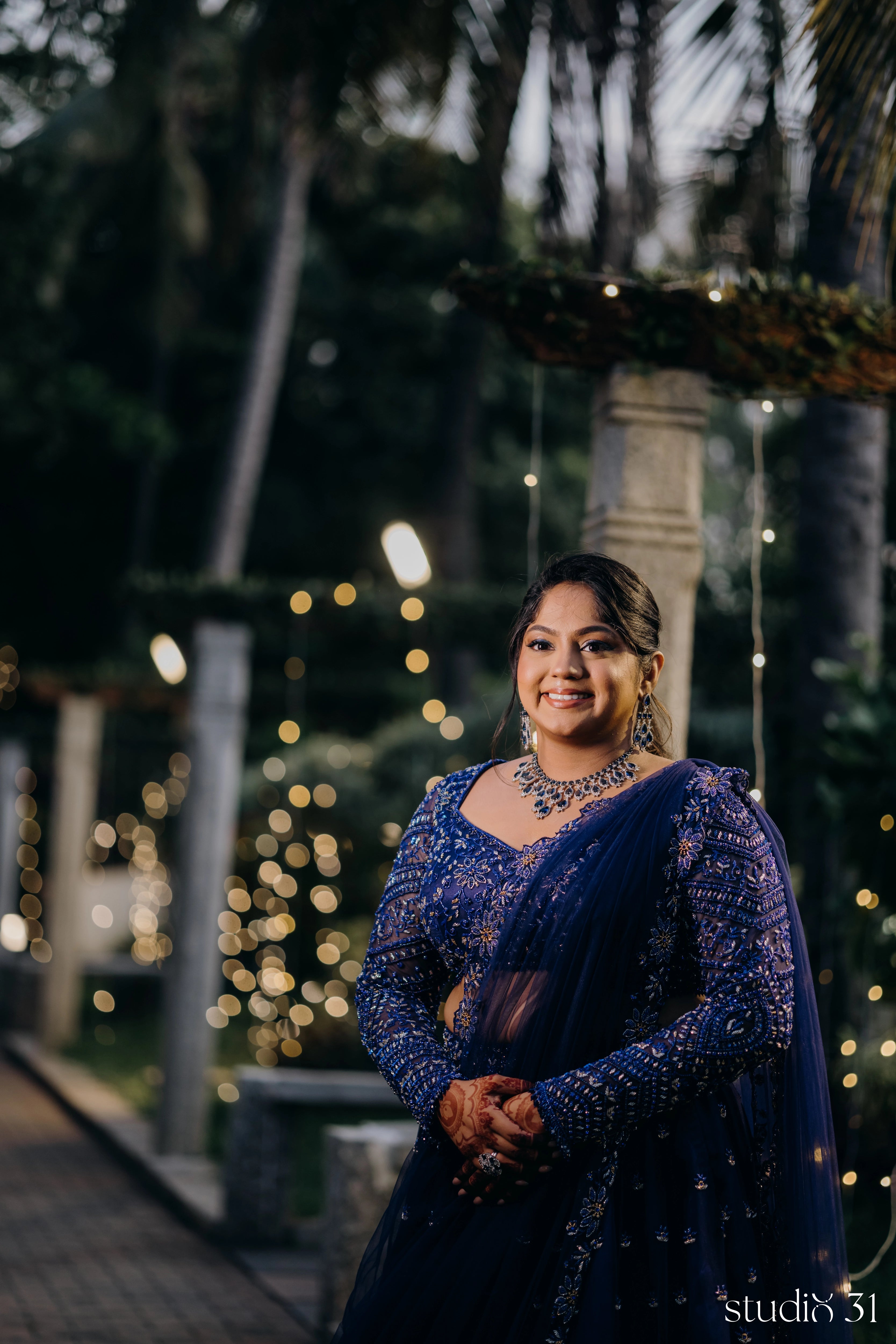 Bride Sambavi from Singapore smiling in a midnight blue lehenga by Archana Karthick