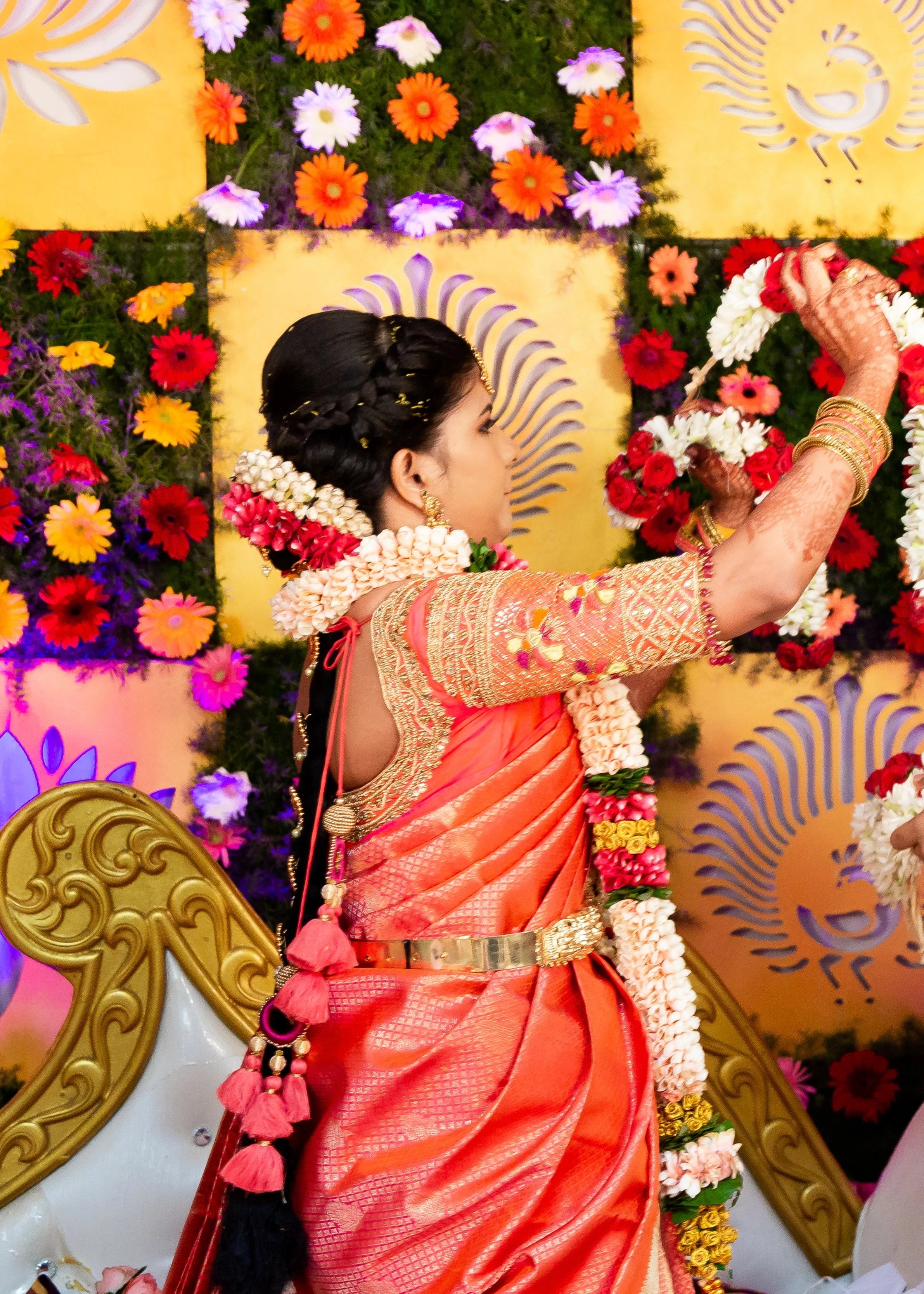 Bride Sarumathi on stage in an orange silk blouse, intricately handcrafted with zardozi, resham, stones and beads by team Archana Karthick.