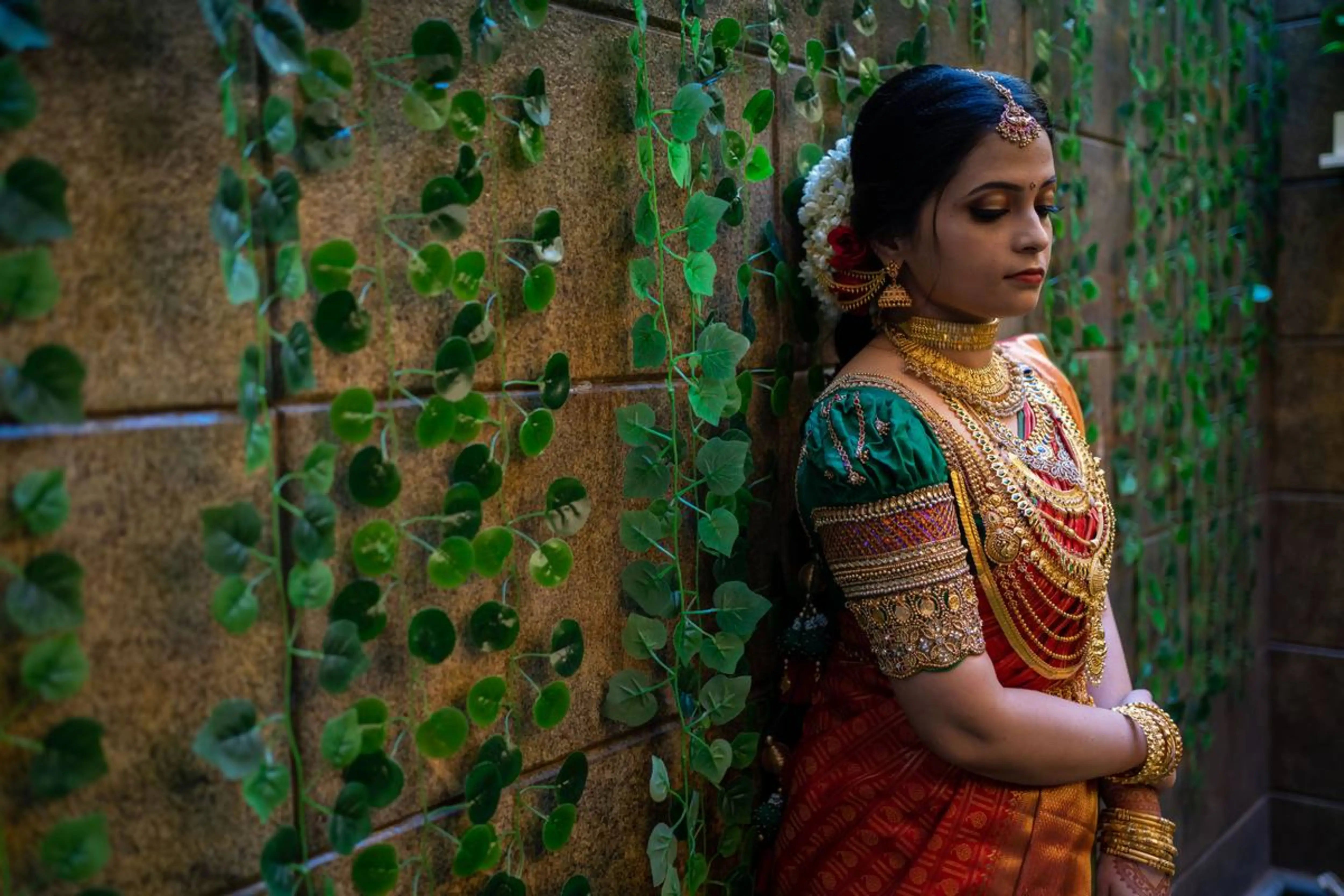 Bride Shalini from Kerala posing for photoshoot in a handcrafted green silk blouse embellished with beads, zardozi, kundan, kemp stones, coins & pearls by team Archana Karthick.