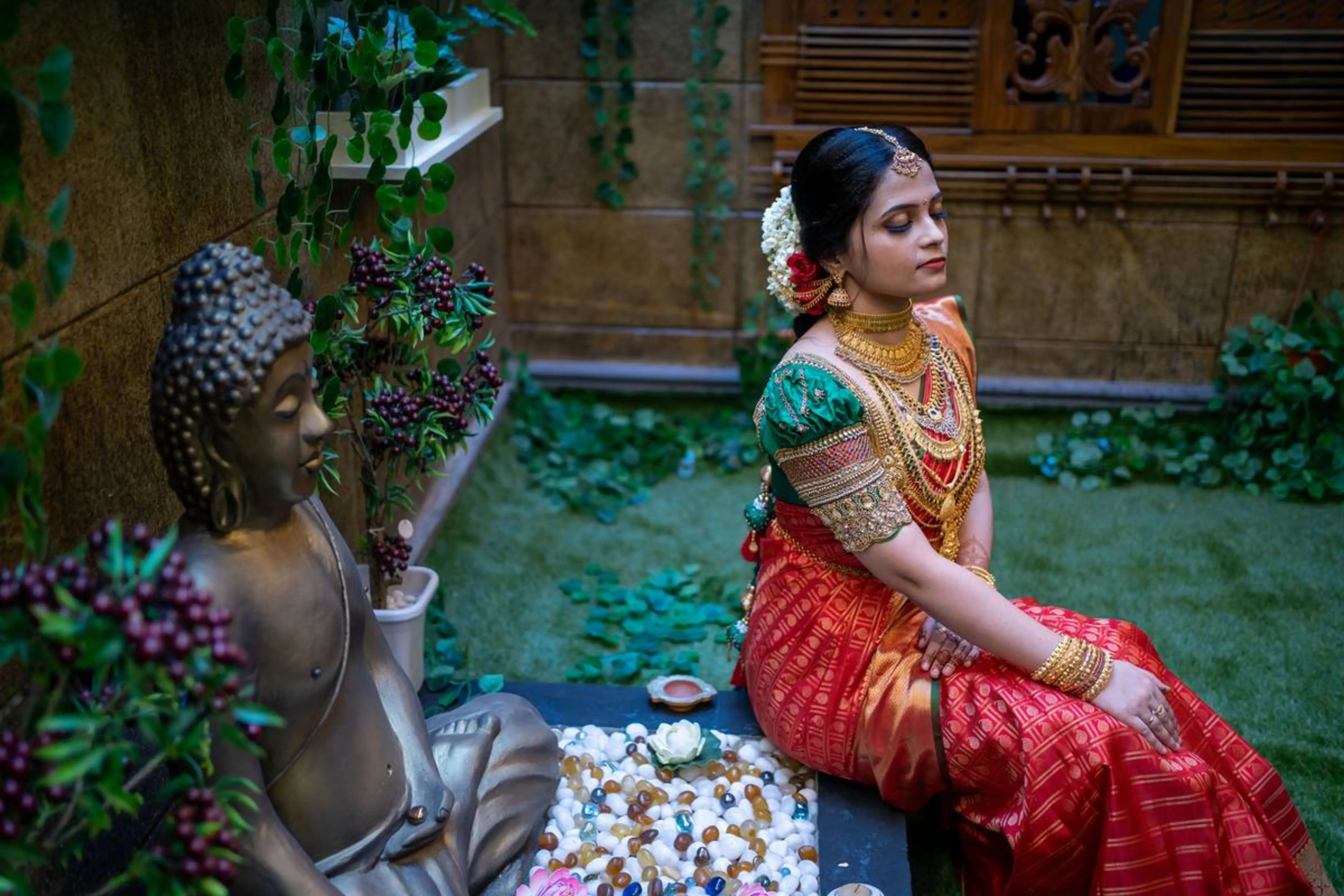 Bride Shalini from Kerala posing seated in a handcrafted green silk blouse embellished with beads, zardozi, kundan, kemp stones, coins & pearls by team Archana Karthick.