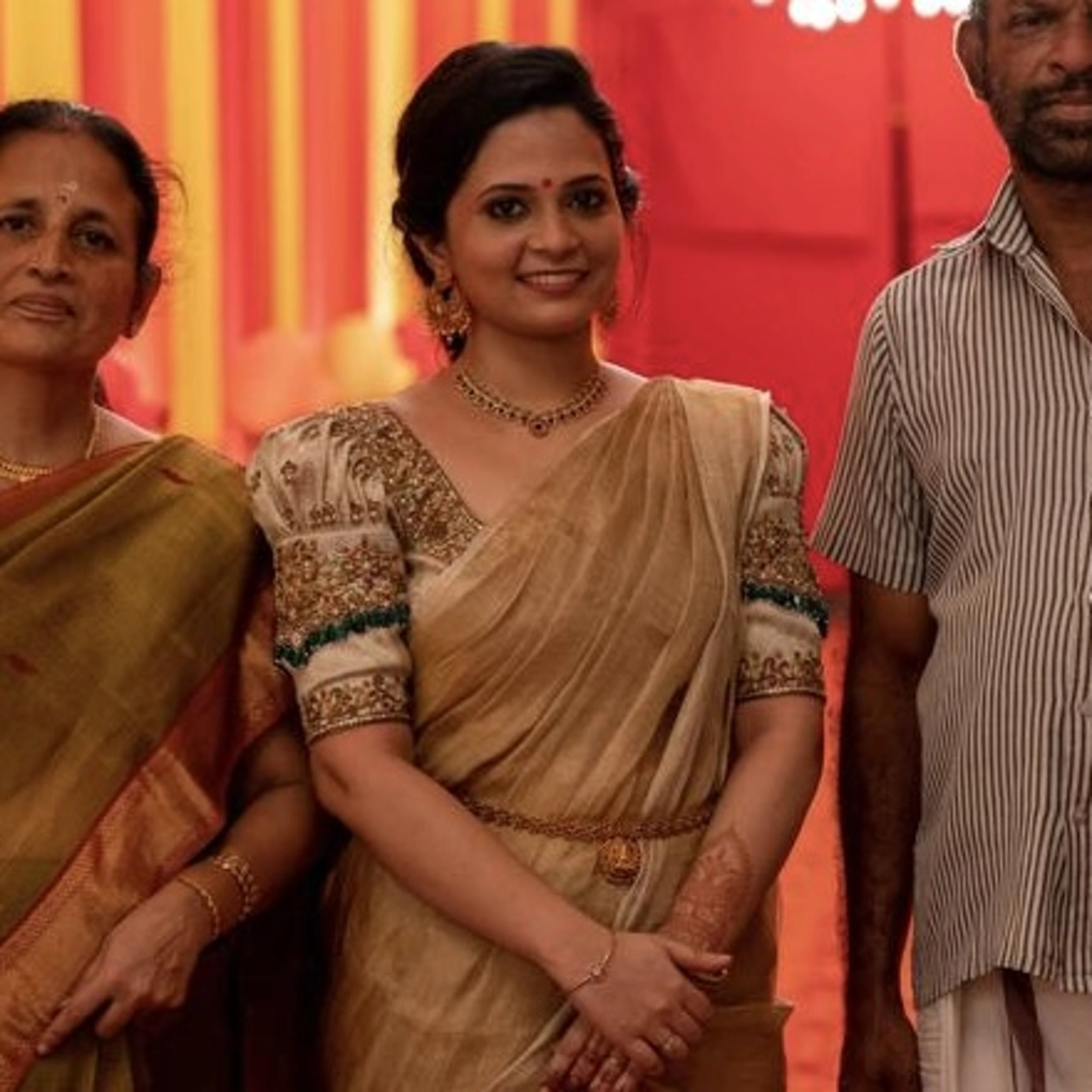 Bride Shalini from Kerala smiling in a handcrafted ivory silk blouse embellished with beads, zardozi, kemp stones & crystals by team Archana Karthick.