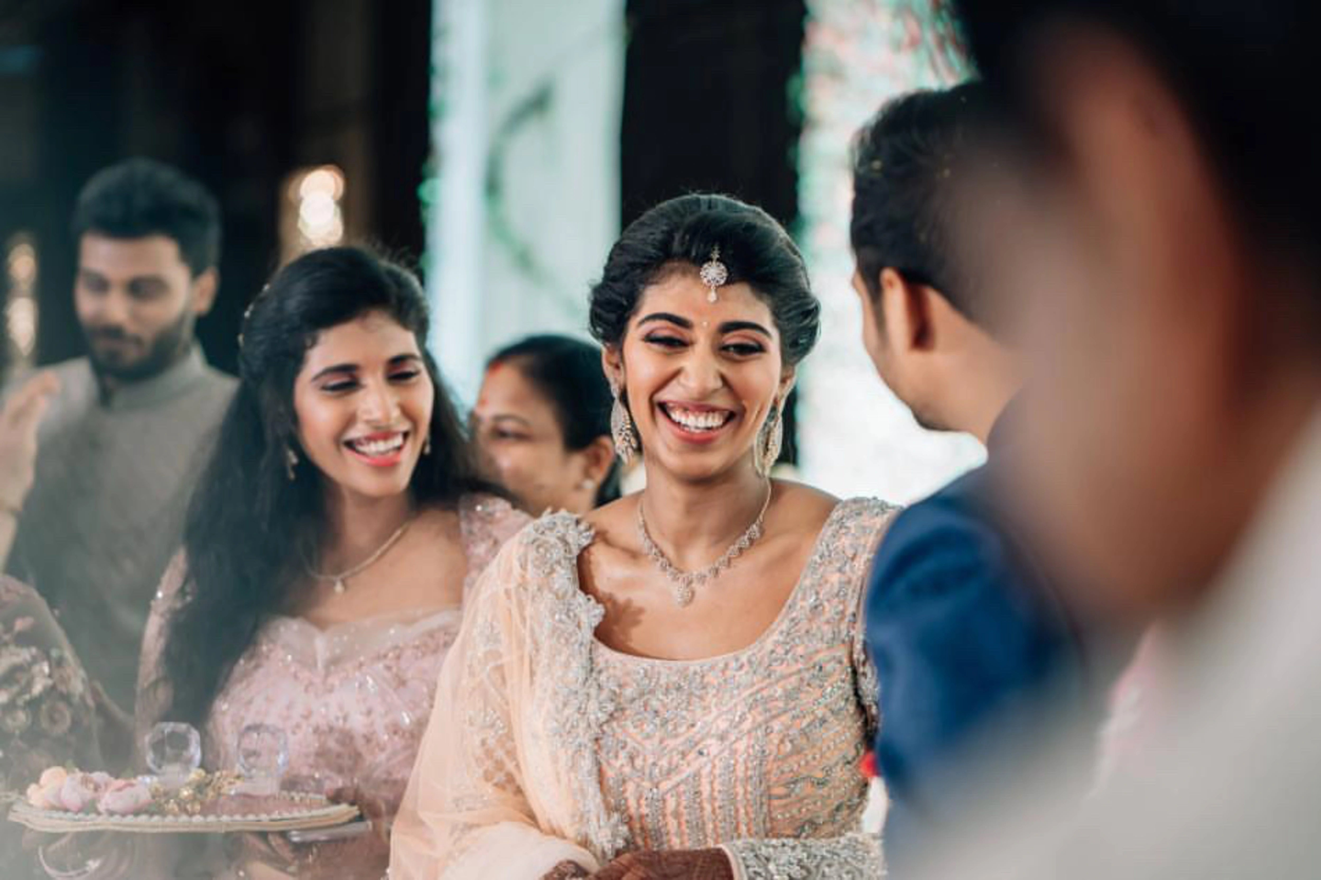 Bride Shanmugapriya smiling in a peach tulle reception lehenga, handcrafted by team Archana Karthick.