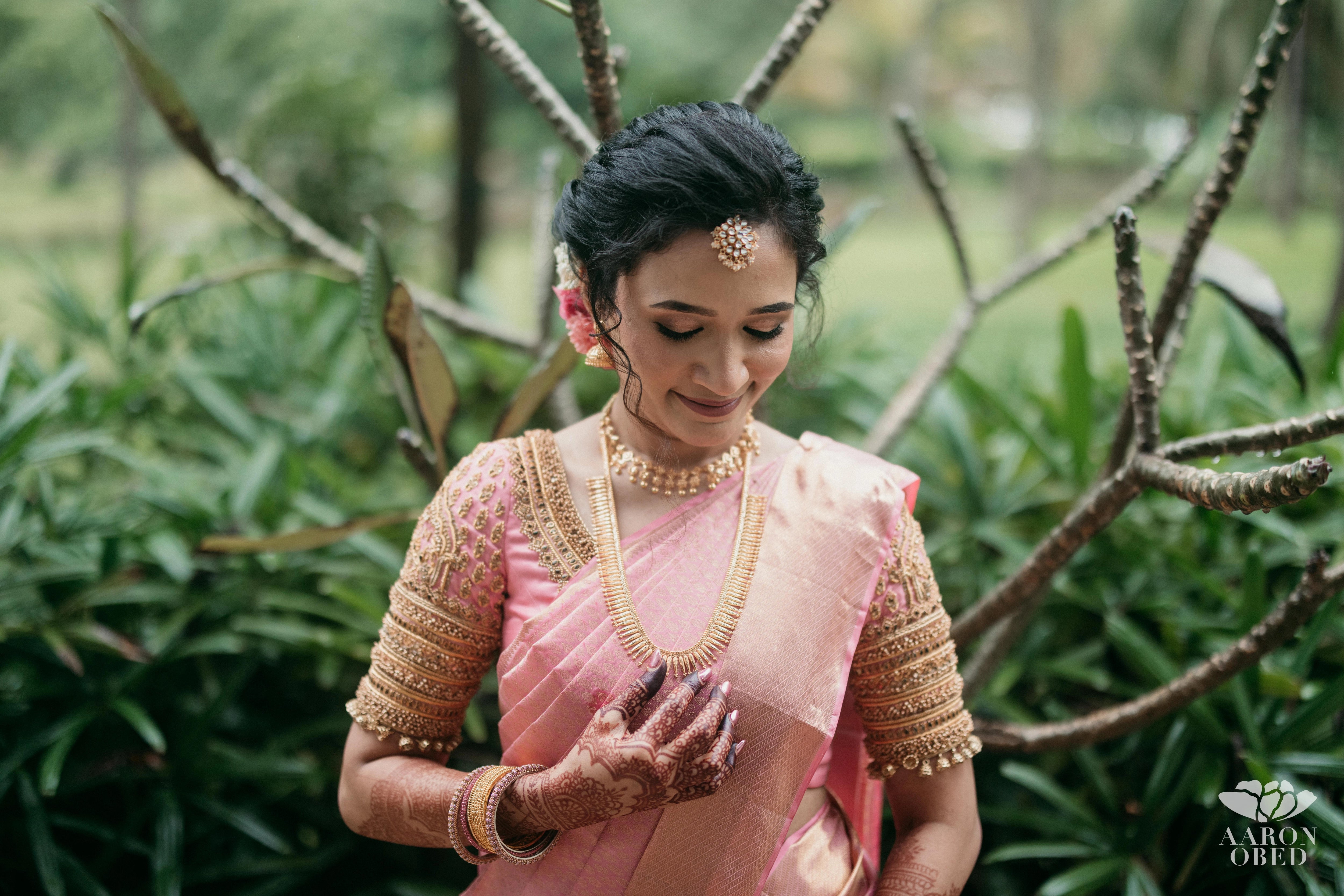 Bride Sharon Jacob in a pink silk blouse, intricately handcrafted with zardozi, stones, sequins and beads by team Archana Karthick.