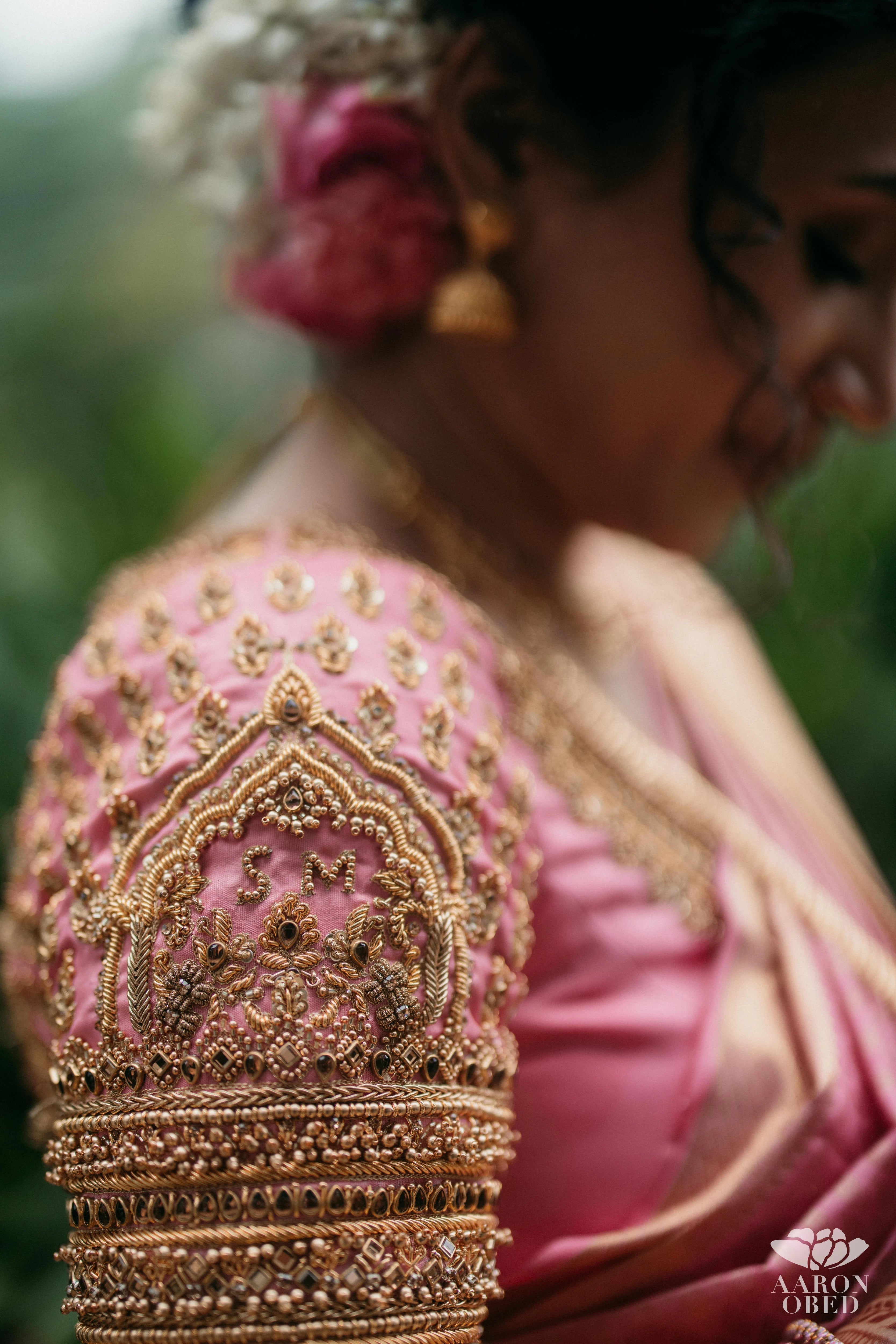 Bride Sharon Jacob showcasing blouse sleeve design in a pink silk blouse, intricately handcrafted with zardozi, stones, sequins and beads by team Archana Karthick.