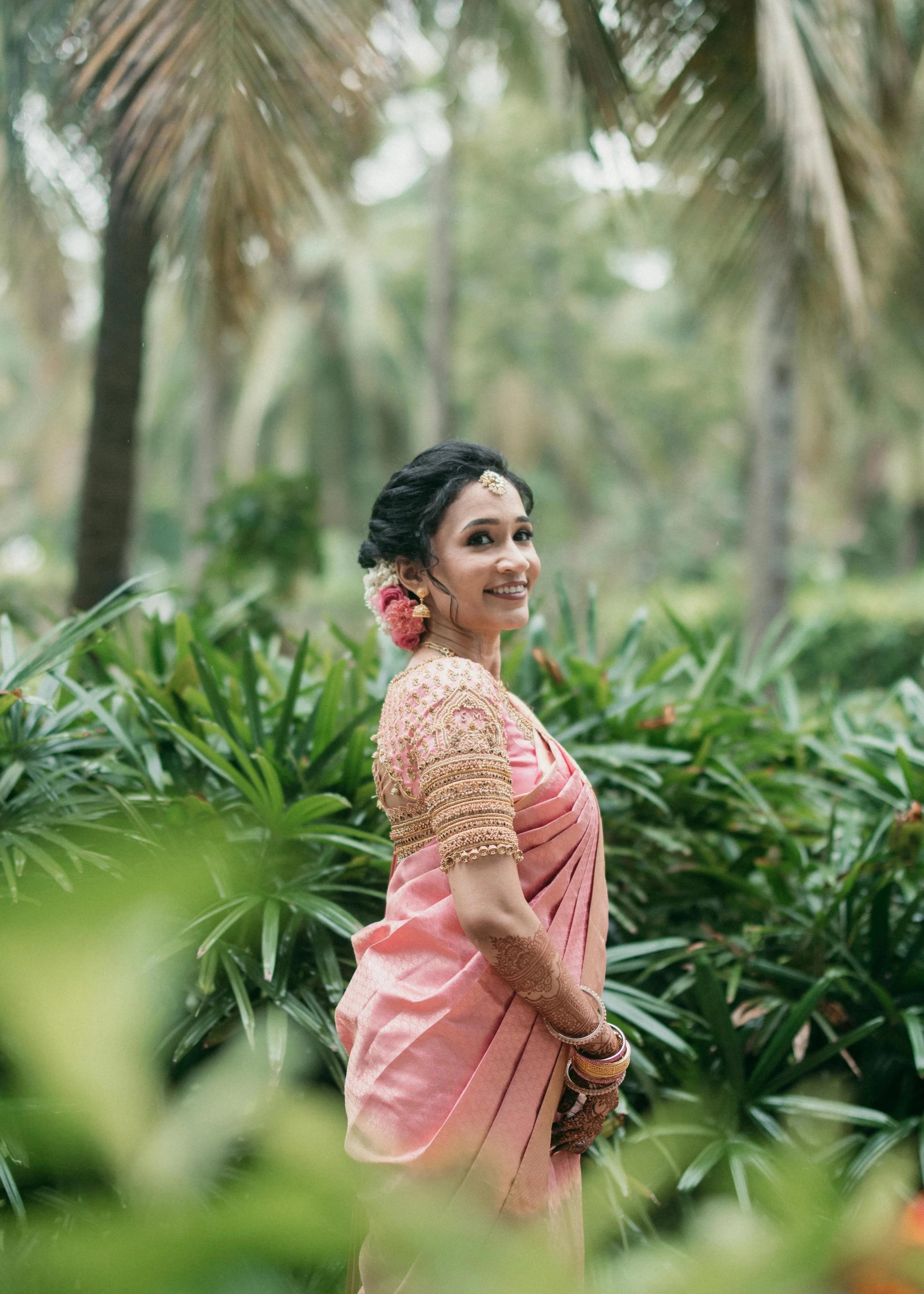 Bride Sharon Jacob smiling in a pink silk blouse, intricately handcrafted with zardozi, stones, sequins and beads by team Archana Karthick.