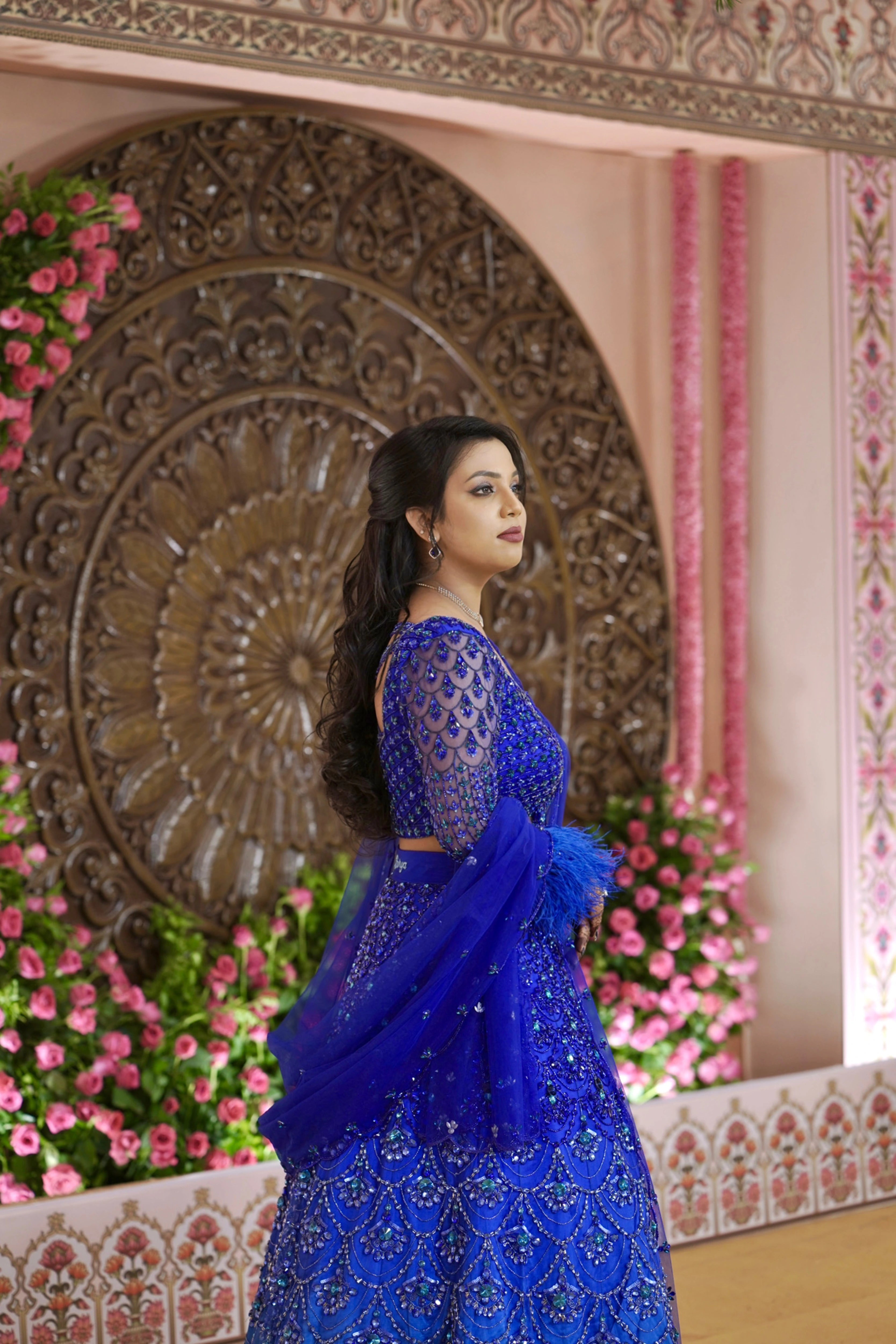 Bride Sharon posing for photo in a peacock themed blue lehenga by Archana Karthick