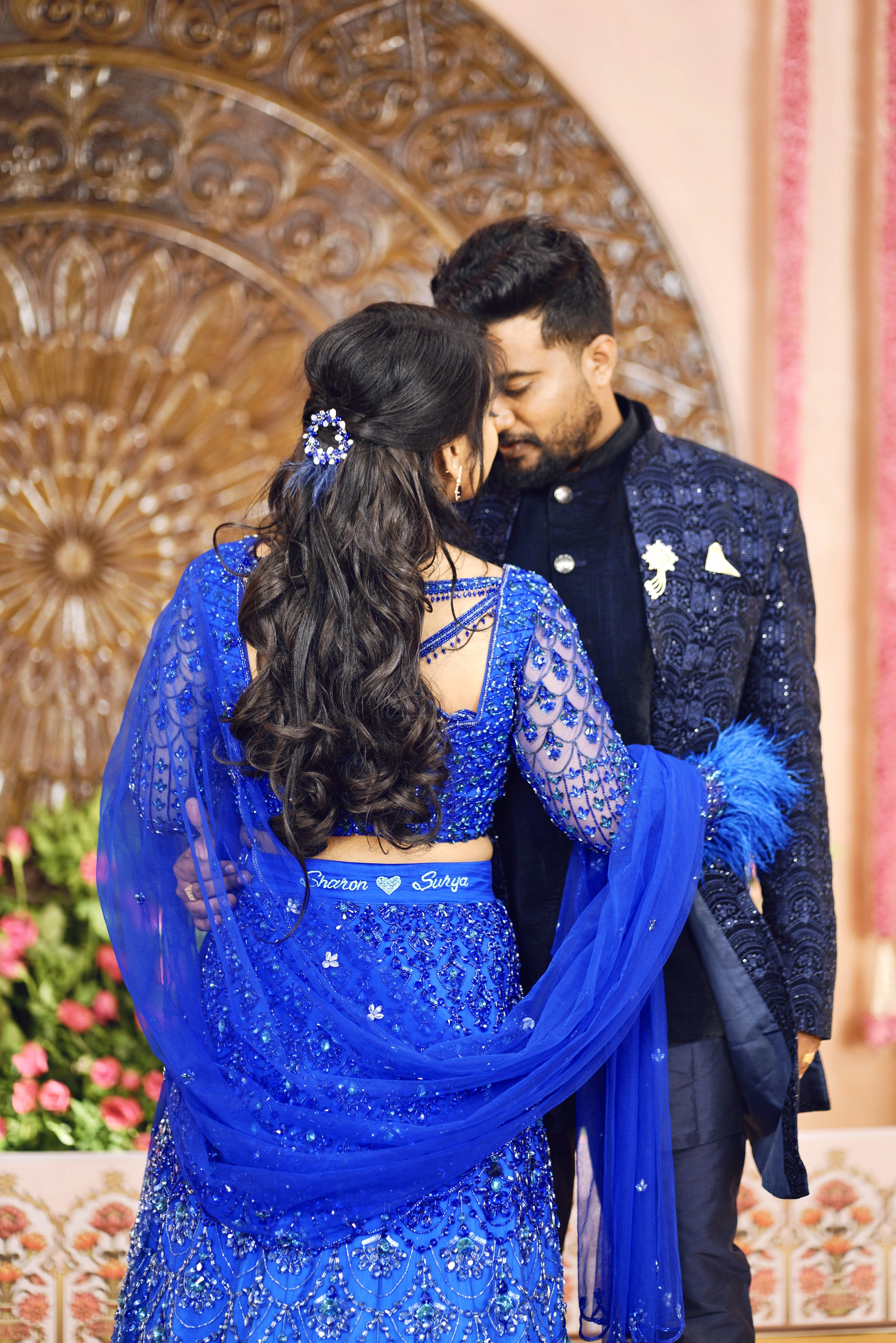 Bride Sharon posing with groom in a peacock themed blue lehenga by Archana Karthick