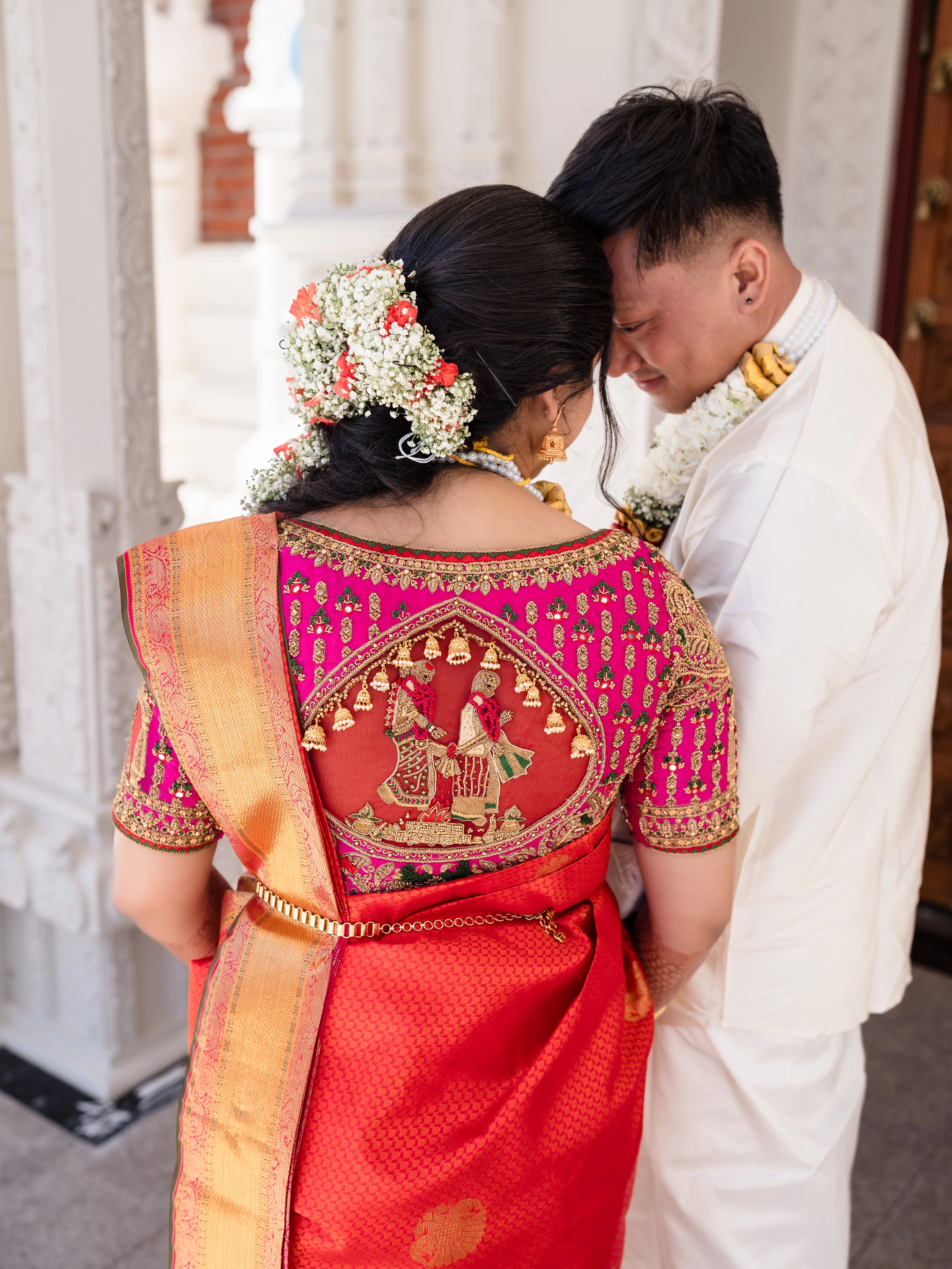 Bride Shivani with groom in a magenta silk blouse, intricately handcrafted with beads, stones, resham, mirrors, jhumkas and zardozi by team Archana Karthick.
