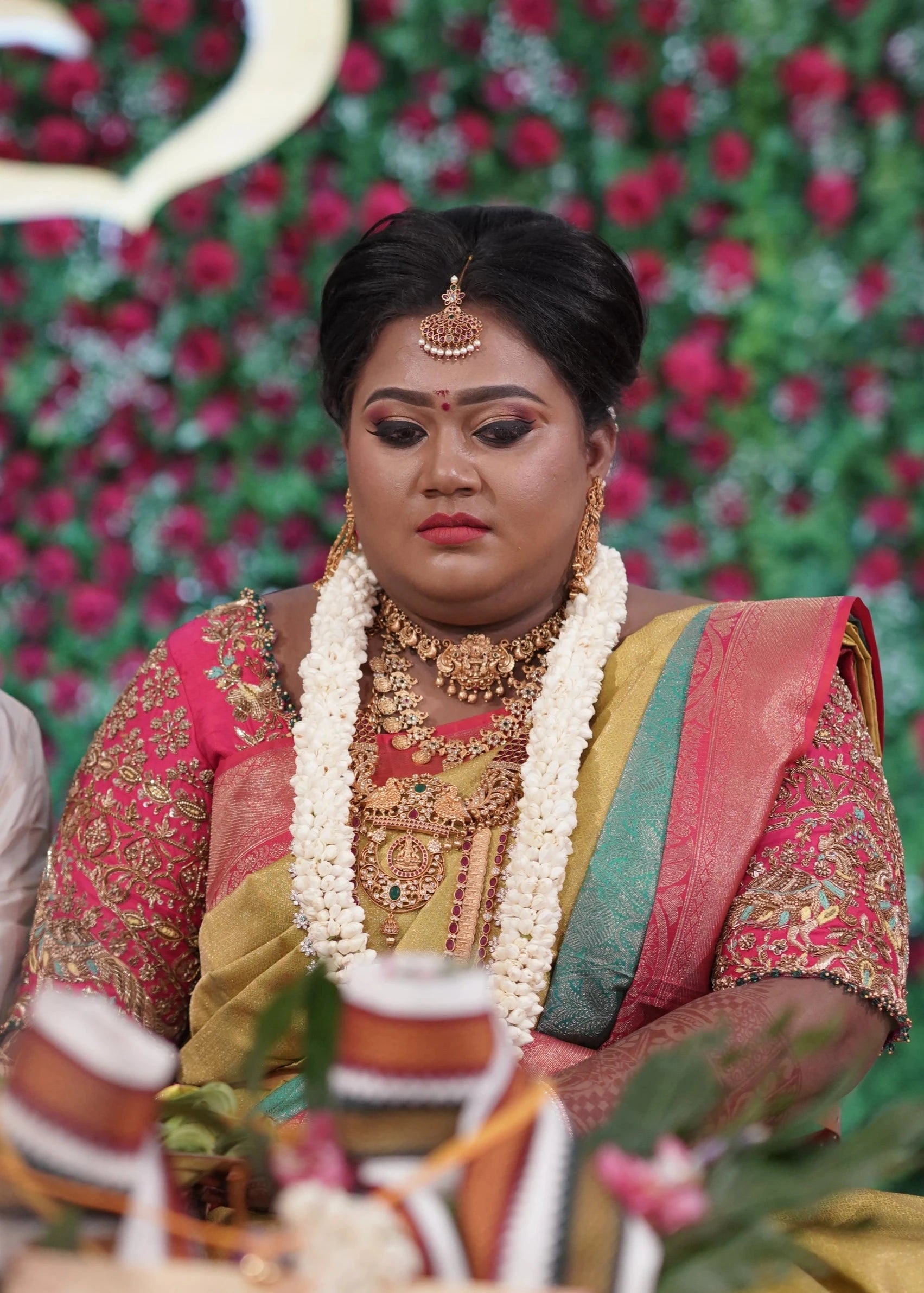 Bride Shyamaladevi in a hot pink raw silk blouse, intricately handcrafted with beads, cutdana, stones, resham, sequins and zardozi by team Archana Karthick.