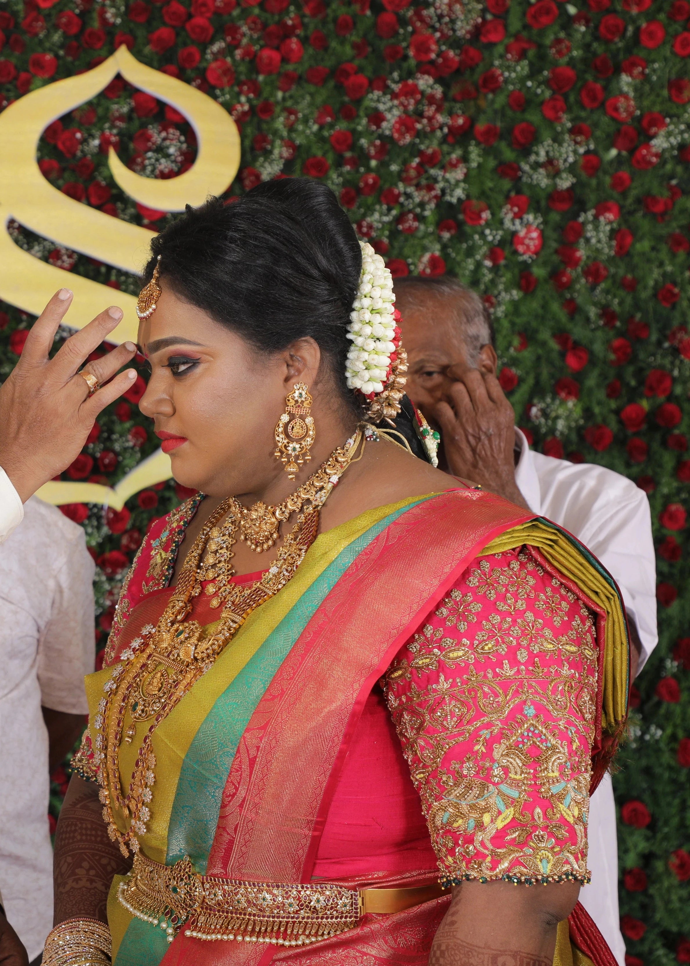 Bride Shyamaladevi on stage in a hot pink raw silk blouse, intricately handcrafted with beads, cutdana, stones, resham, sequins and zardozi by team Archana Karthick.