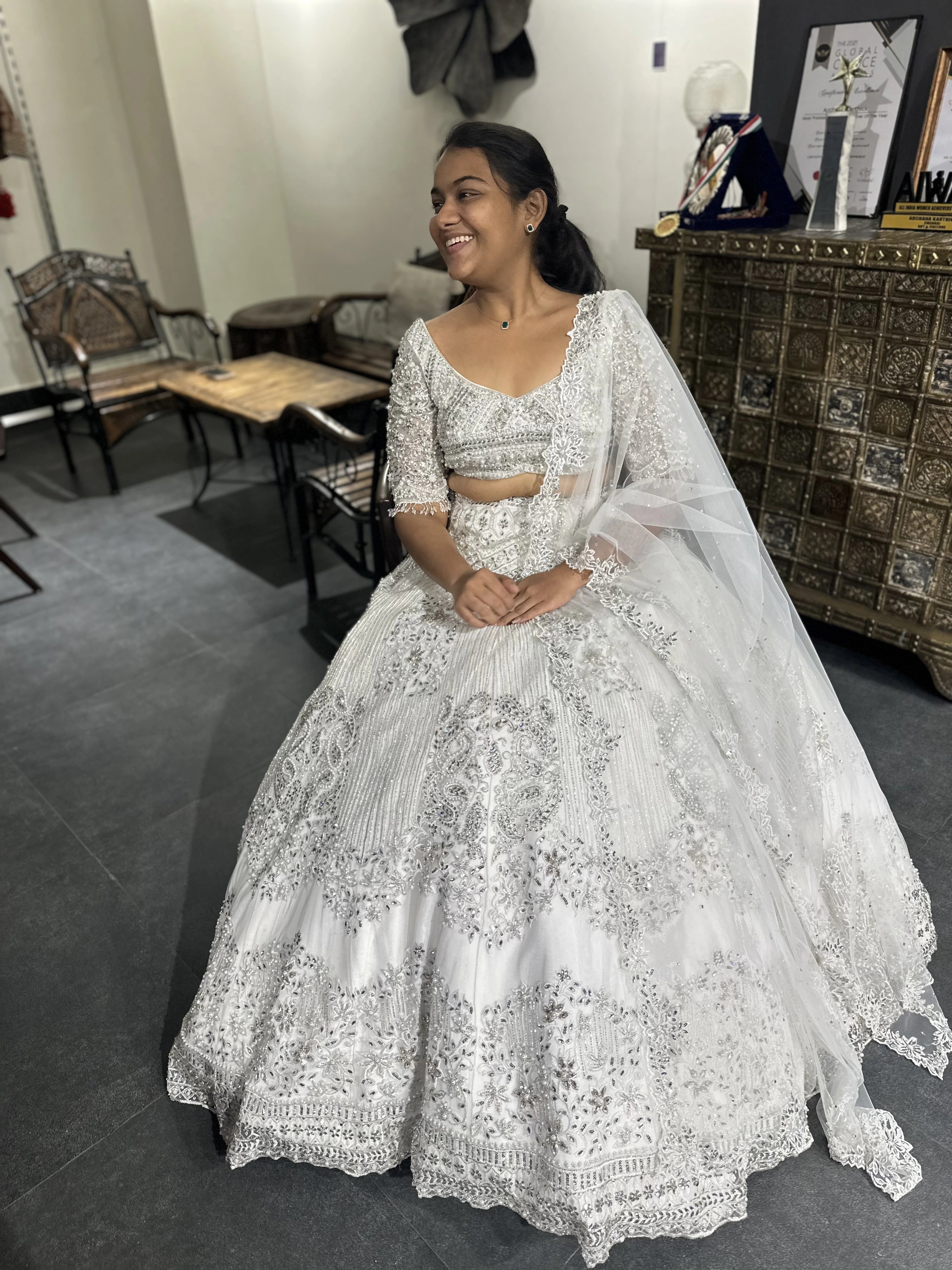 Bride Sneha from Chennai smiling in a silver raw silk lehenga, intricately handcrafted with zari, cutdana, zardozi, crystals and stones by team Archana Karthick.
