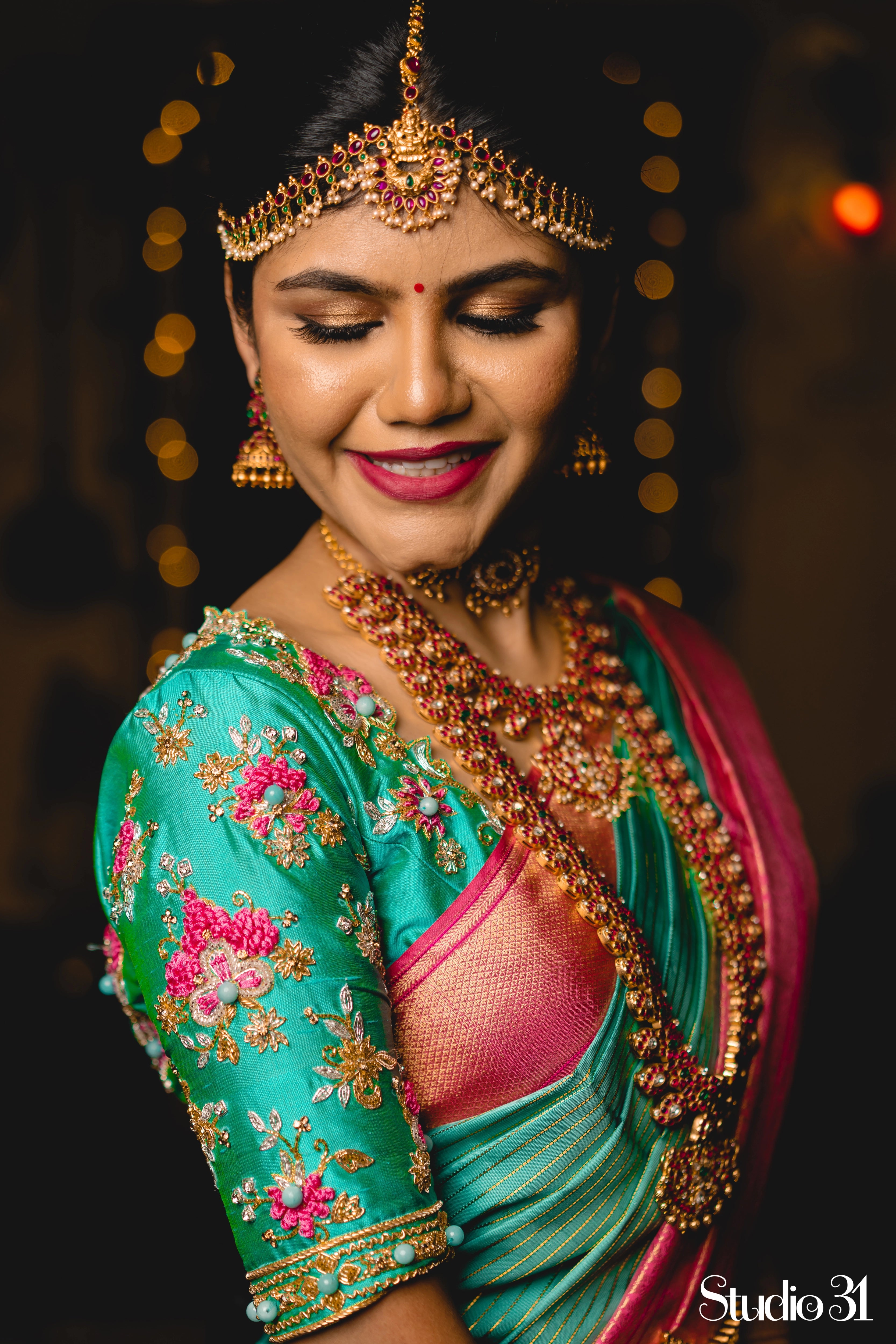 Bride Sruthi Venkatesan from USA, posing for photoshoot in a teal silk blouse by team Archana Karthick.