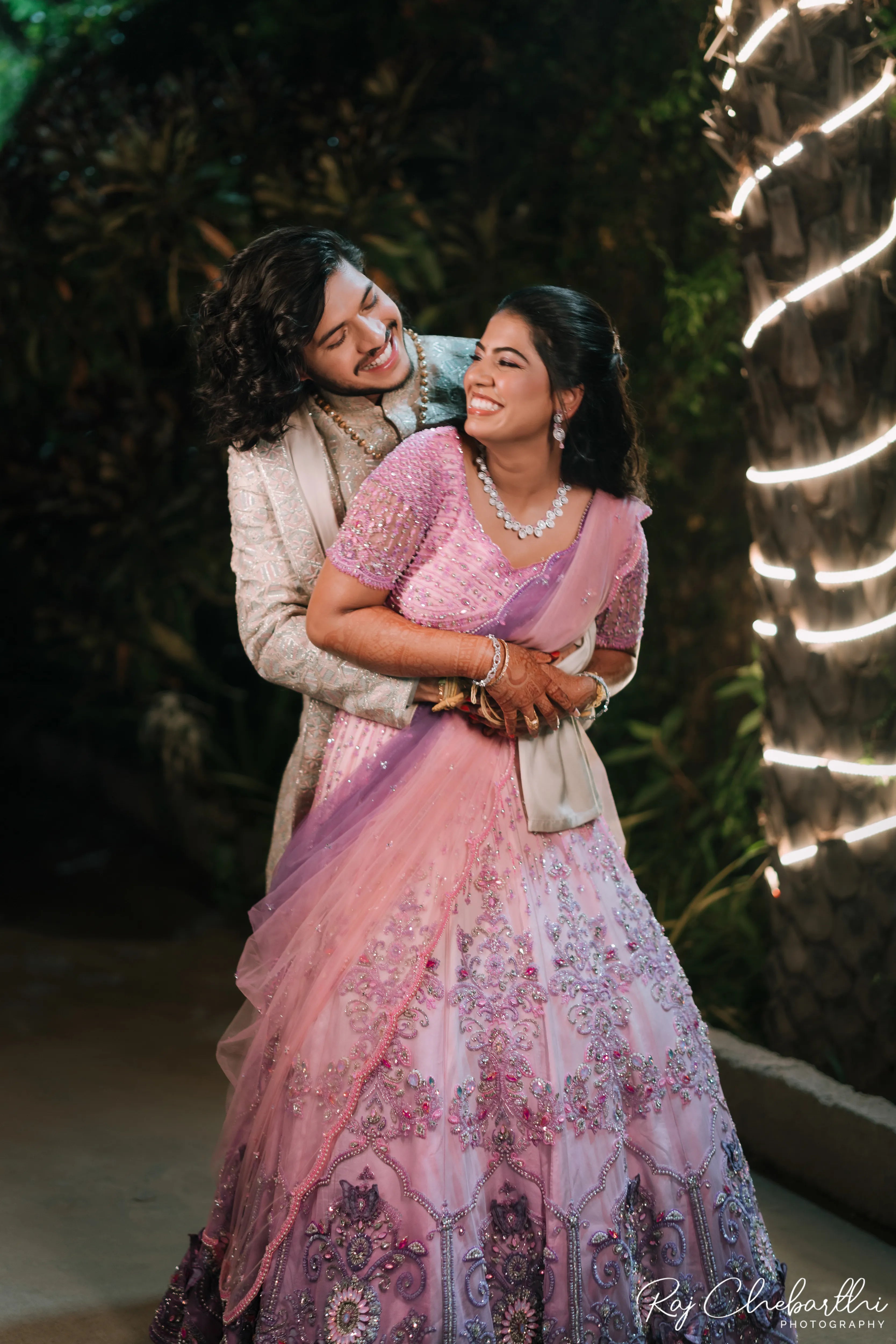 Bride Subhiksha from US posing and smiling with groom in a lavender-pink lehenga by Archana Karthick