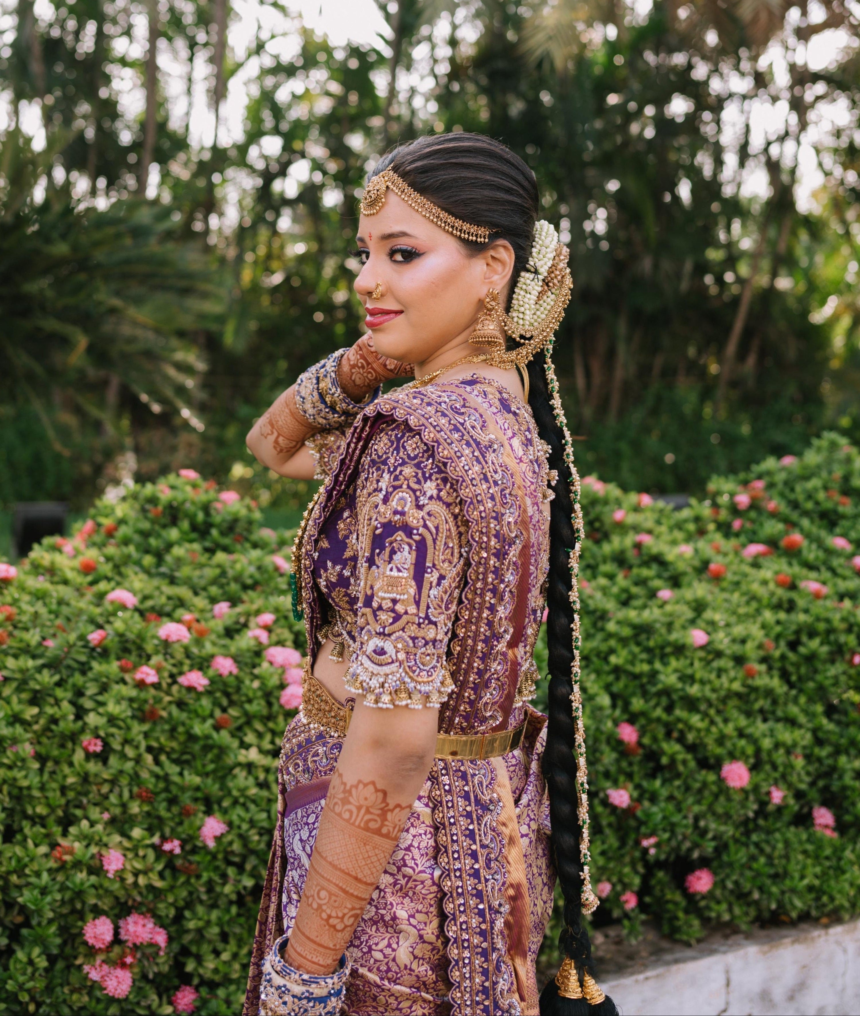 Bride Urmila posing elegantly looking to her left in a handcrafted blouse and saree border for her wedding muhurtham designed by Archana Karthick. Sleeves and saree border detailing captured well.