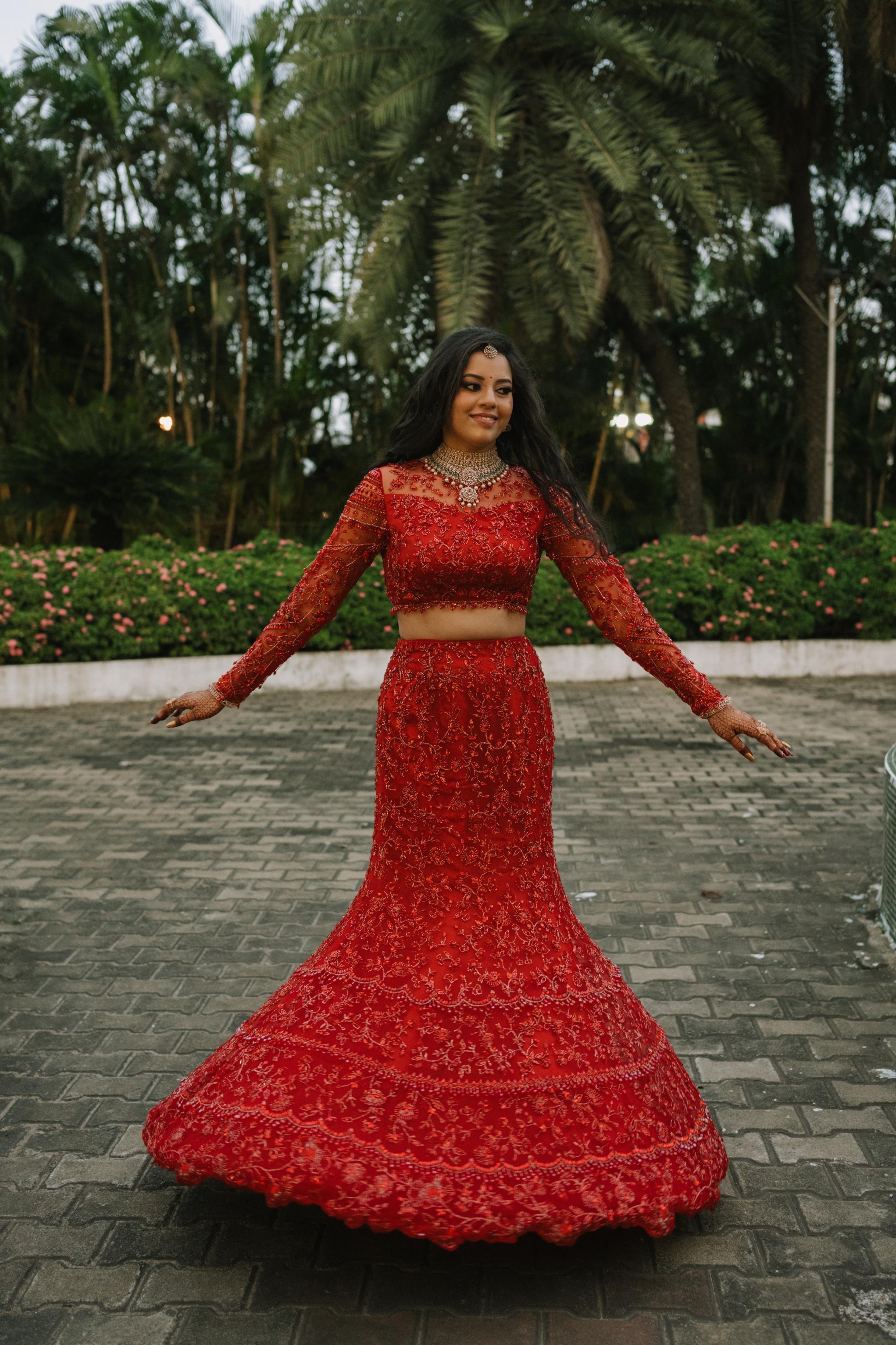 Bride Urmila twirling for her reception in a red handcrafted mermaid lehenga drape designed by Archana Karthick.