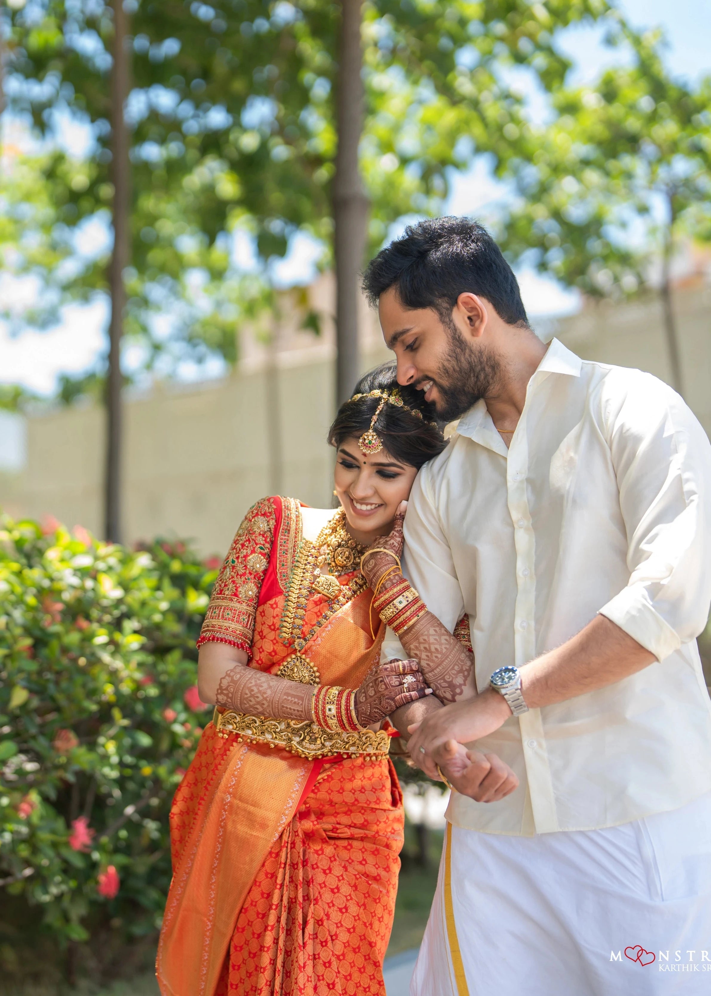 Bride Vaishali Dheenan in an embrace with groom in a red silk blouse for her muhurtham, handcrafted with zardozi, sequins, kundan, crystals, beads and resham by team Archana Karthick.