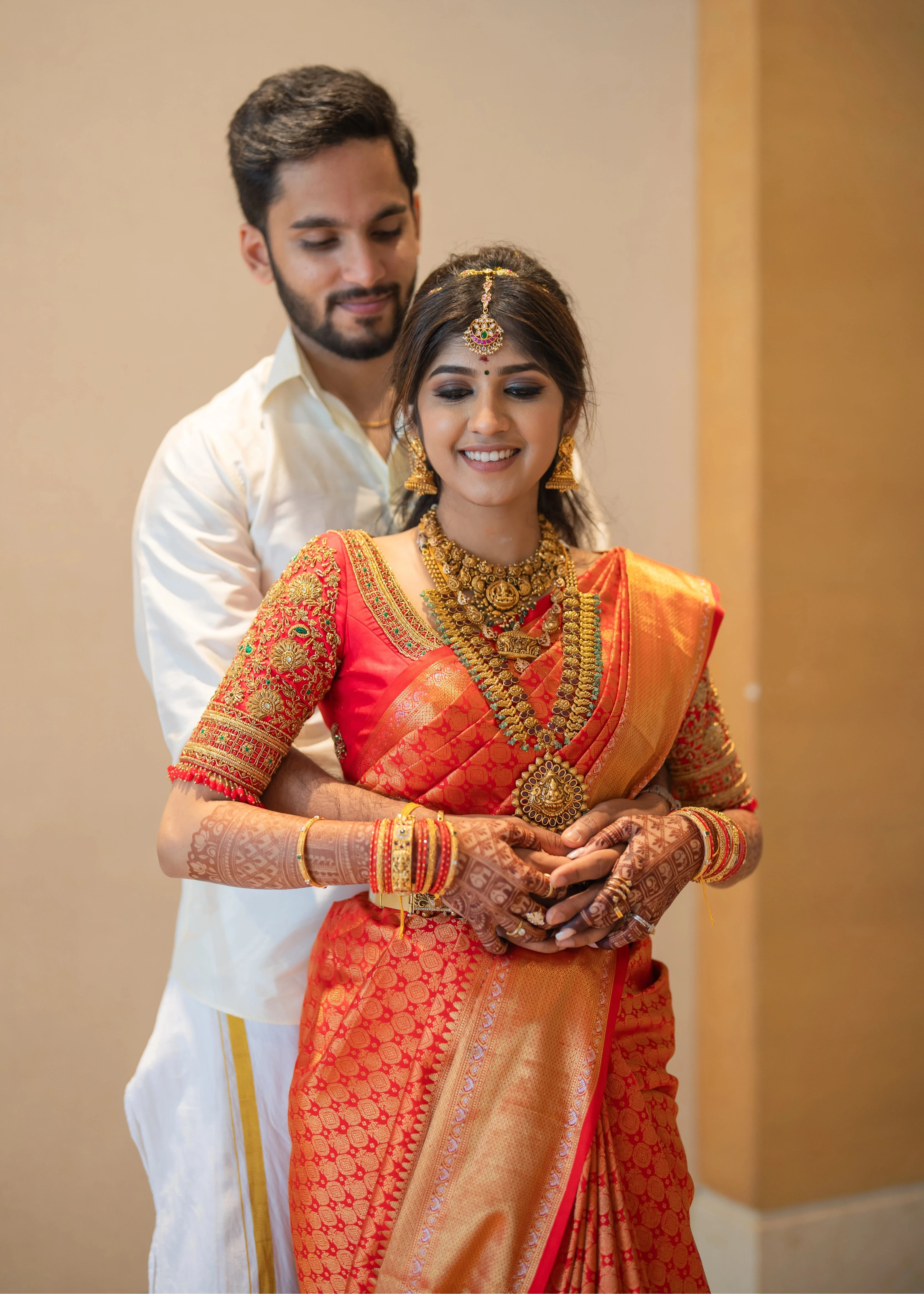 Bride Vaishali Dheenan with groom in a red silk blouse for her muhurtham, handcrafted with zardozi, sequins, kundan, crystals, beads and resham by team Archana Karthick.