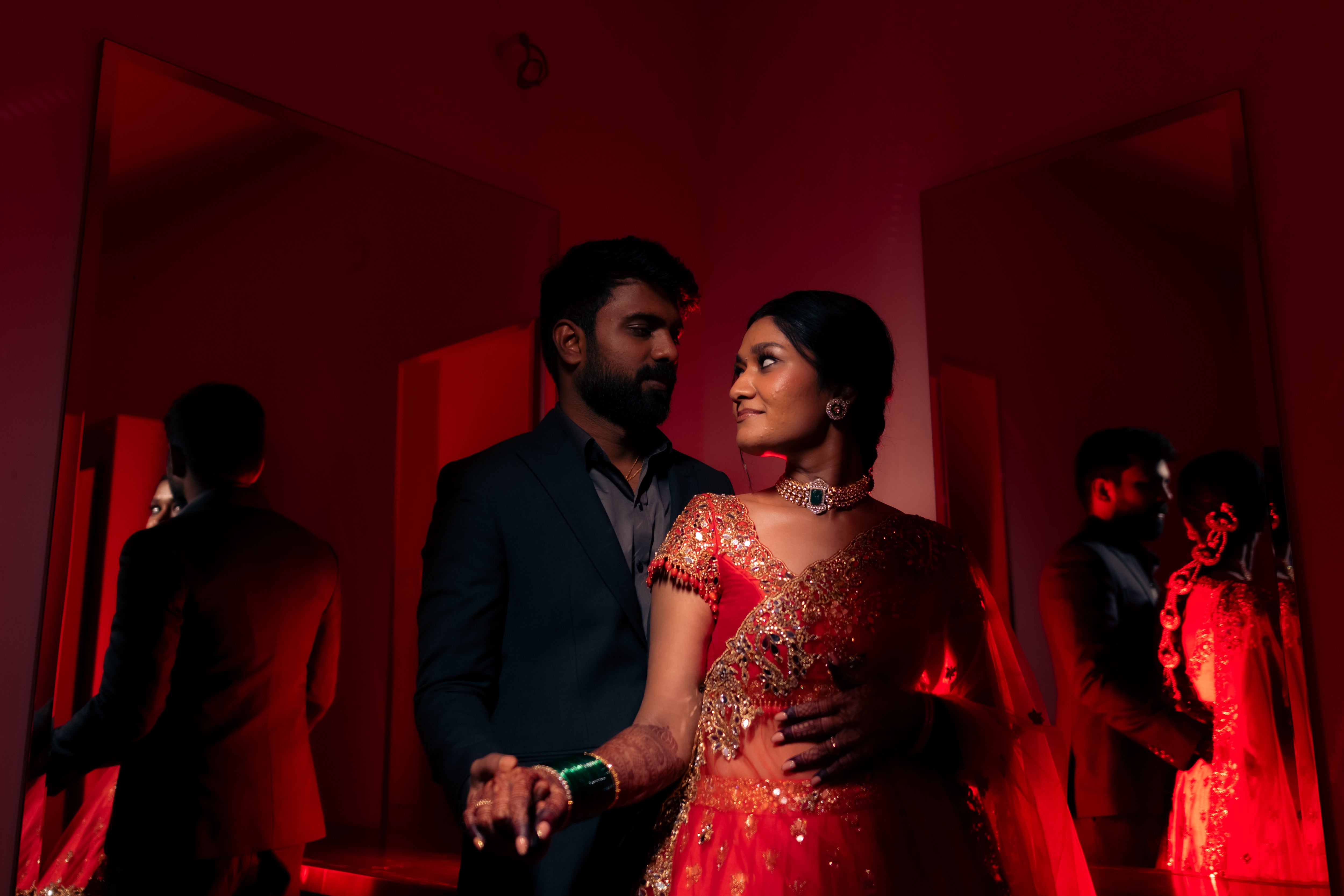Bride Vaishali from Dubai, in a stunning mirror and zardozi worked orange lehenga designed by Archana Karthick. Here the bride is posing with the groom looking at each other.