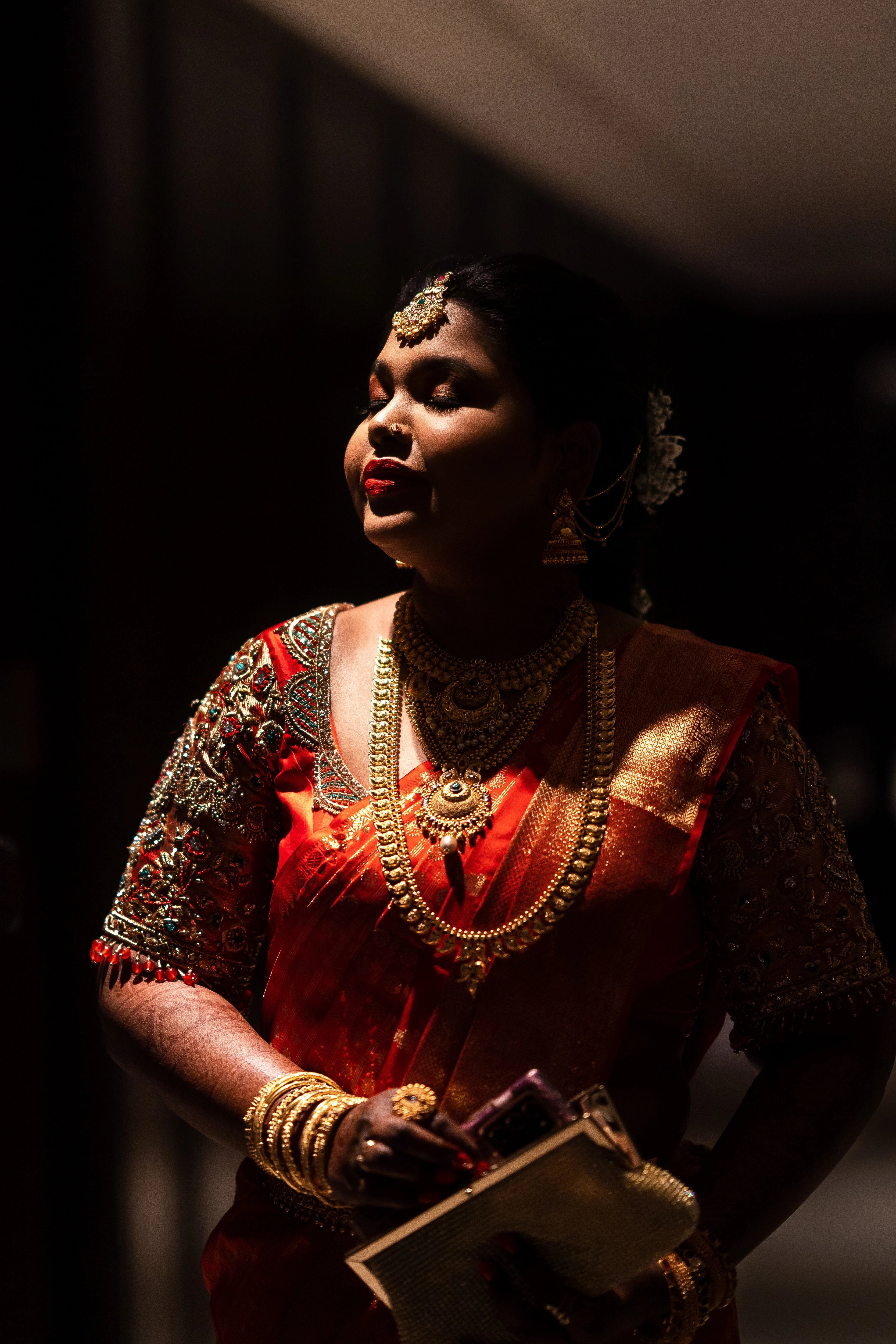 Bride Vanmathi from Chennai posing in a red and gold silk blouse for her wedding, handcrafted with zardozi, stones, kundan, beads and resham by team Archana Karthick.