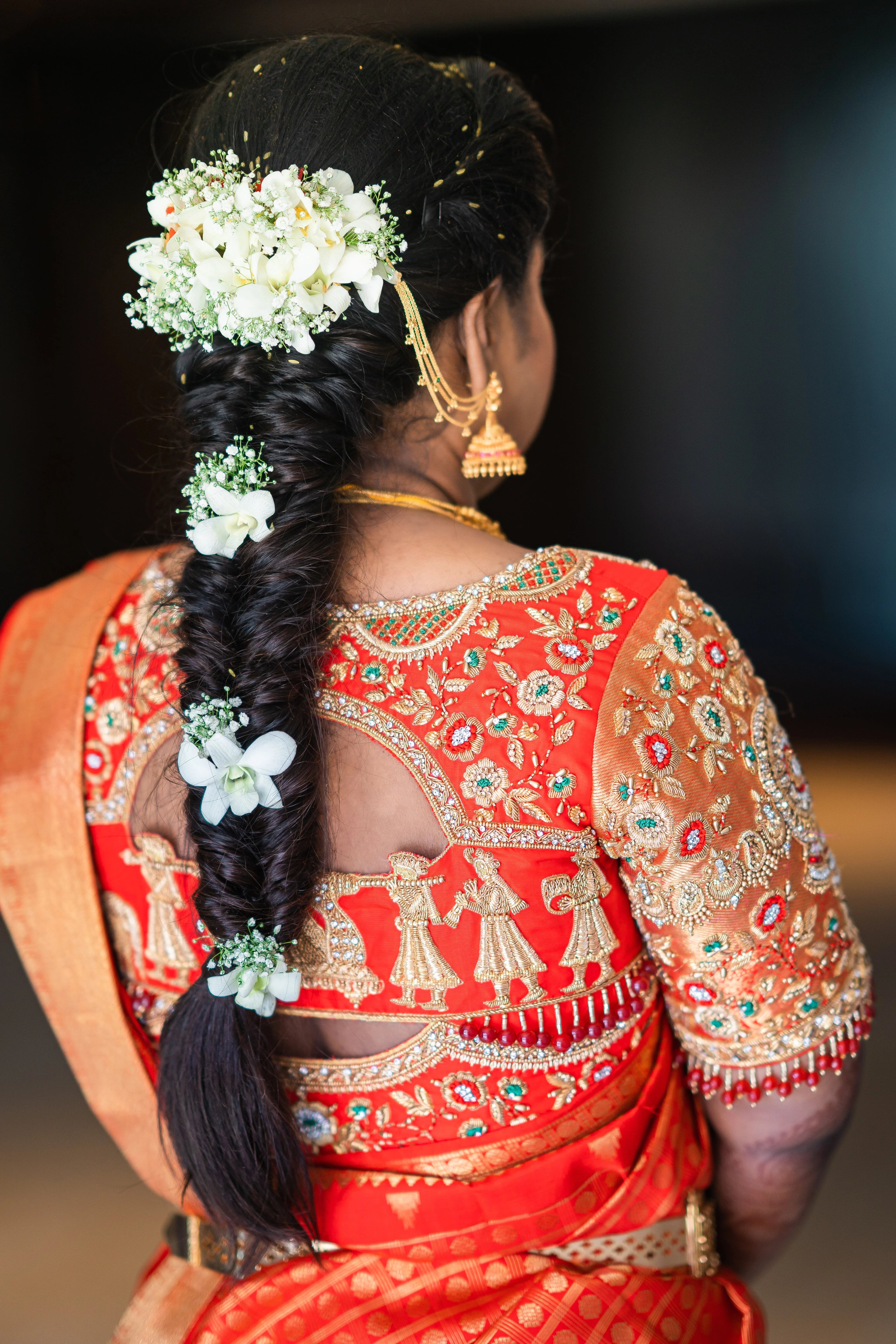 Bride Vanmathi from Chennai showcasing back blouse design in a red and gold silk blouse for her wedding, handcrafted with zardozi, stones, kundan, beads and resham by team Archana Karthick.