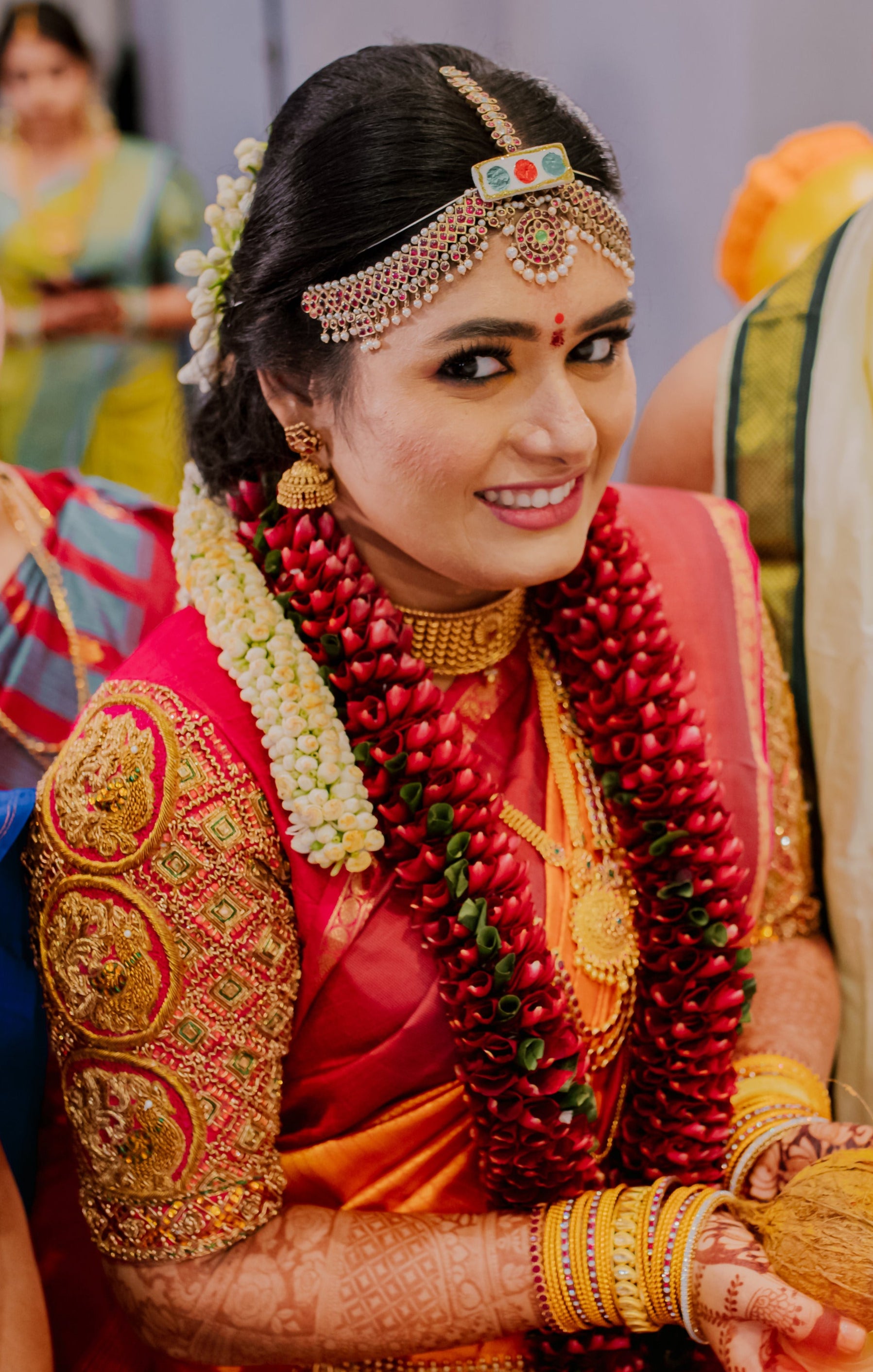Bride Varshini in a handcrafted red silk blouse designed by Archana Karthick. She is in the middle of accepting the offerings.