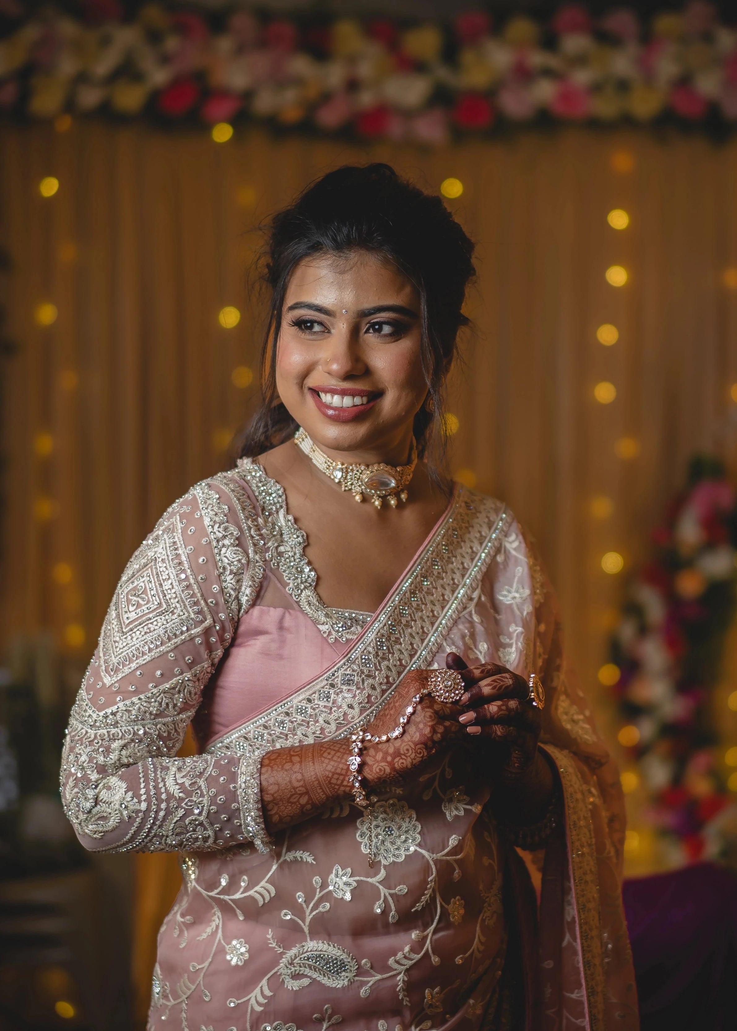 Bride Vidhira smiling in a soft blush tulle blouse for her reception, handcrafted with rhinestones, resham and crystals by team Archana Karthick.