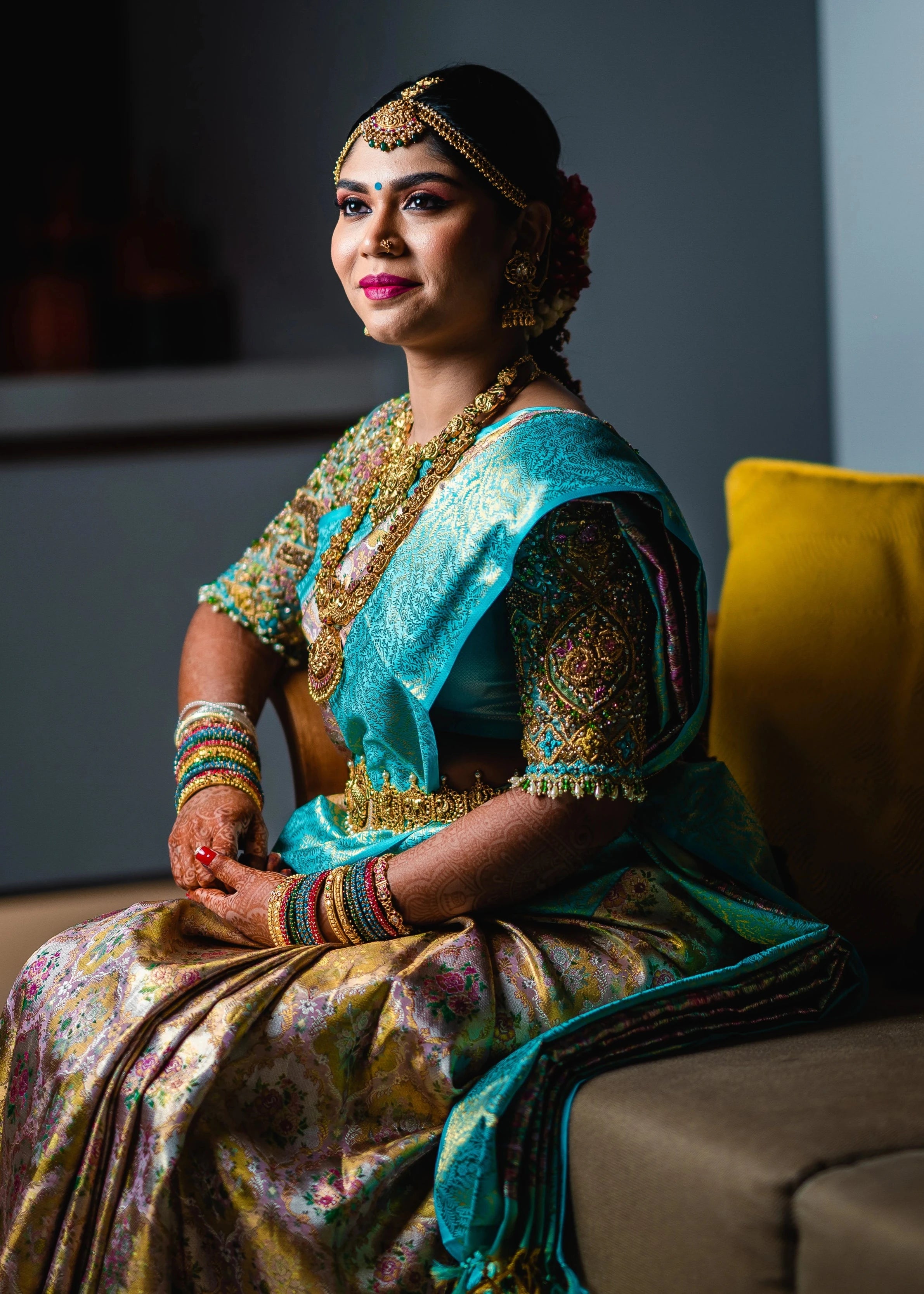 Bride Vidya D posing seated in a powder blue silk blouse, handcrafted with beads, zardozi, kundan, resham, stones and crystals by team Archana Karthick.