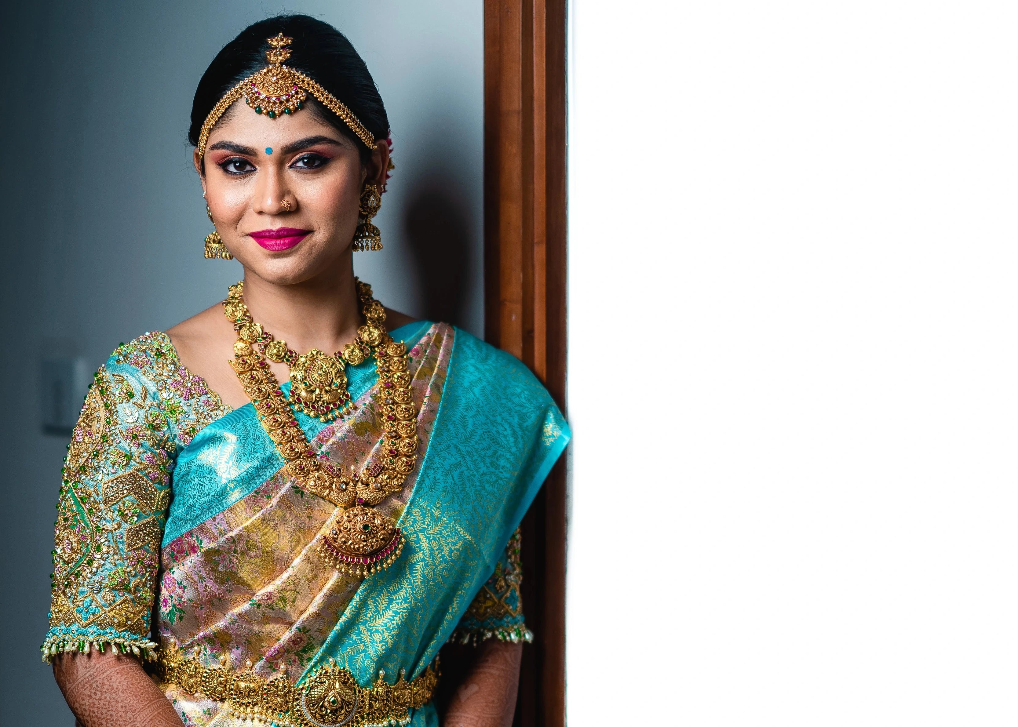Bride Vidya D posing with a smile in a powder blue silk blouse, handcrafted with beads, zardozi, kundan, resham, stones and crystals by team Archana Karthick.