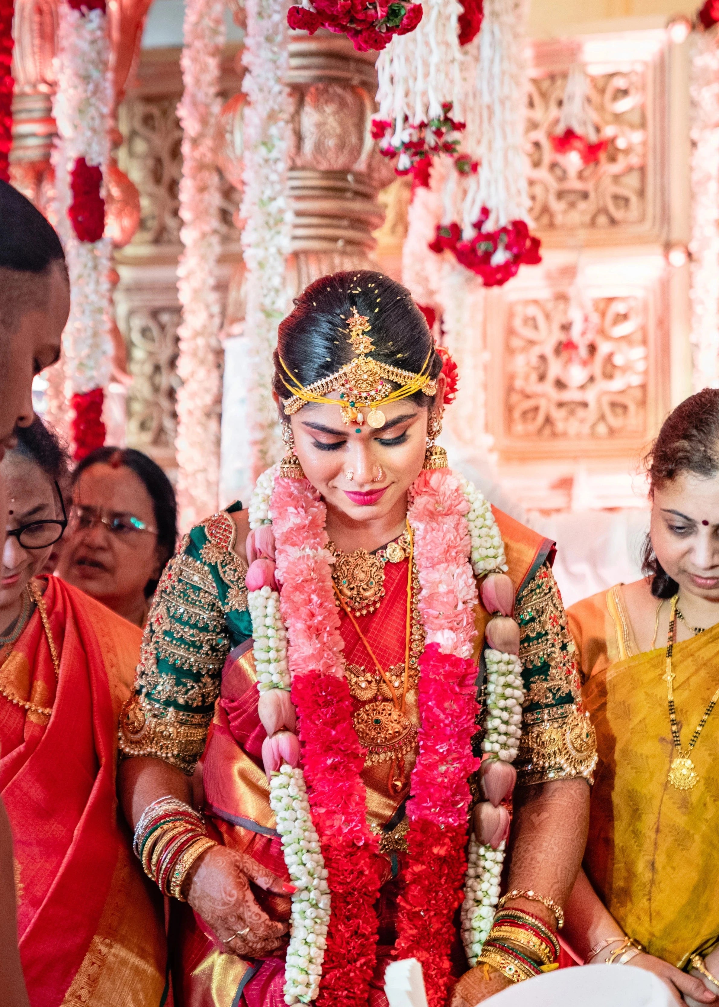 Bride Vidya D posing with garland in a bottle green silk blouse, handcrafted with beads, zardozi, kundan, resham, stones and coins by team Archana Karthick.