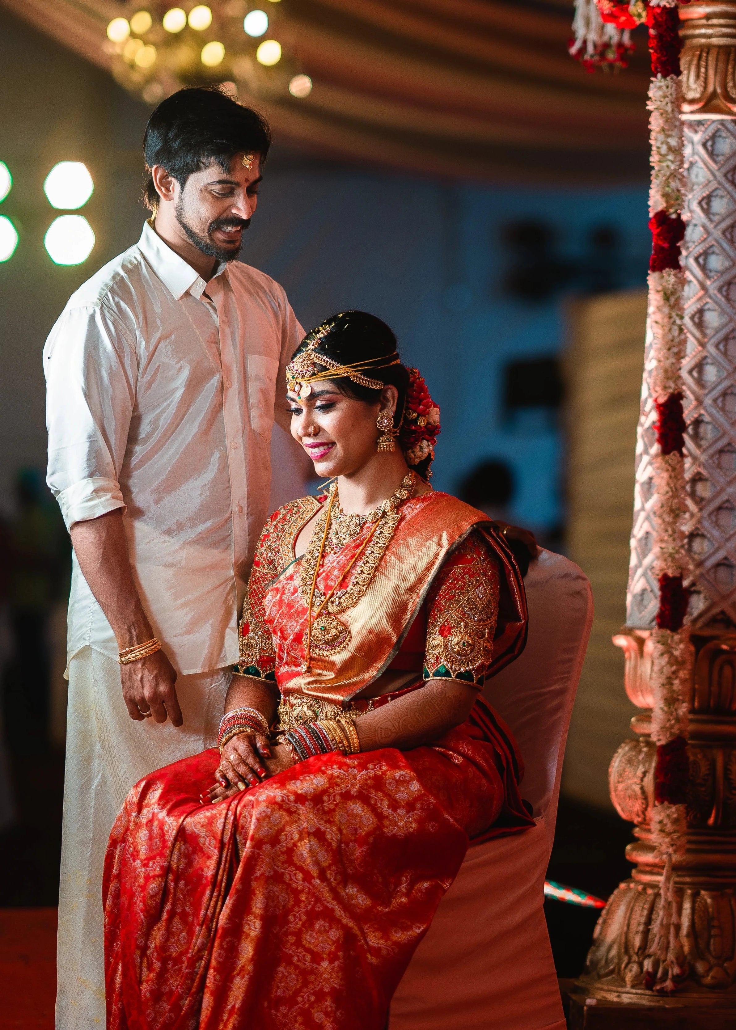 Bride Vidya D with groom in an orange silk blouse, handcrafted with beads, zardozi, kundan, resham, stones and zardozi by team Archana Karthick.