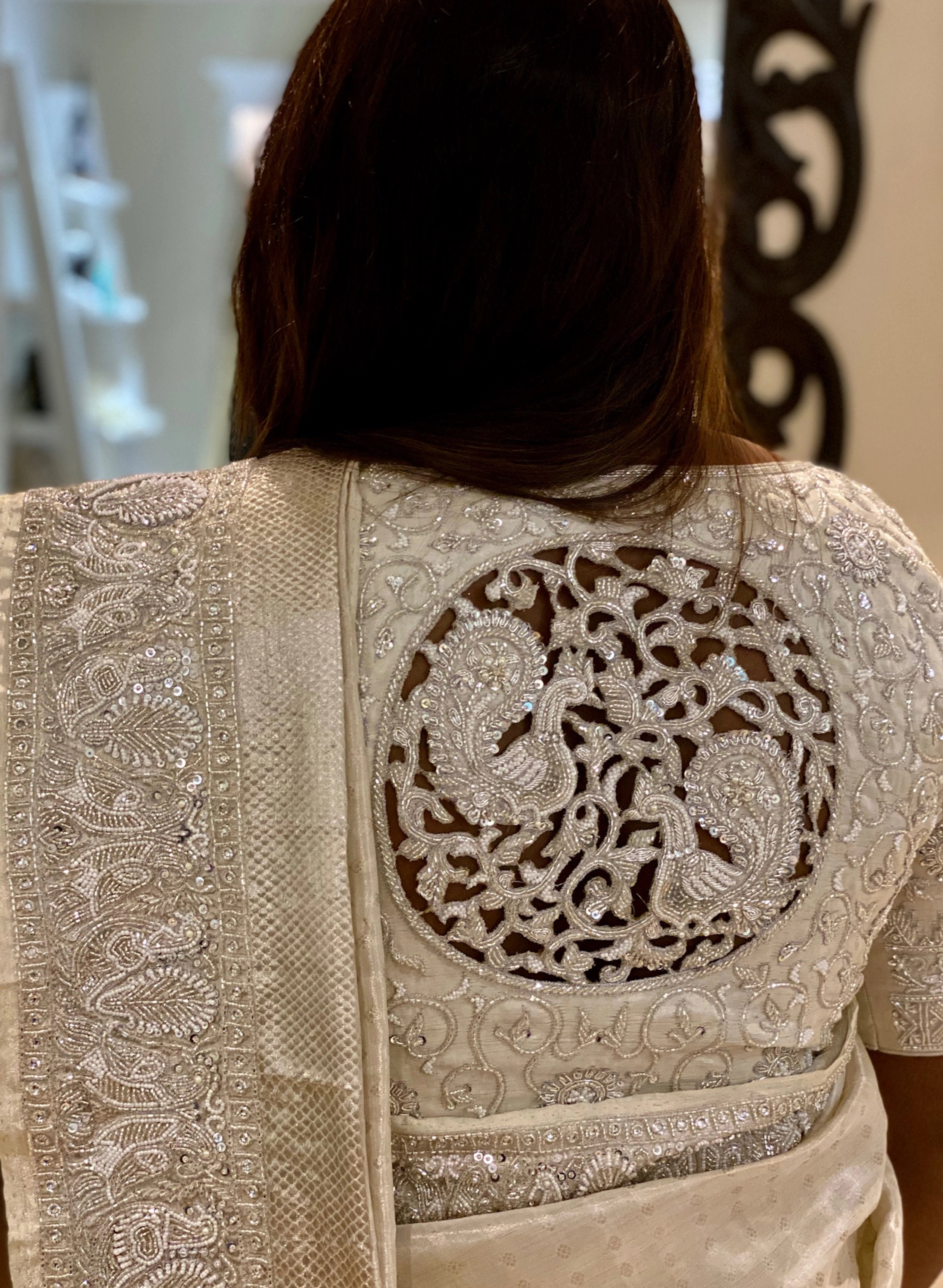 Bride Viniba from Chennai showcasing back design in an ivory and silver silk blouse and saree border handcrafted intricately with beads, stones, sequins, cutdana and zardozi.