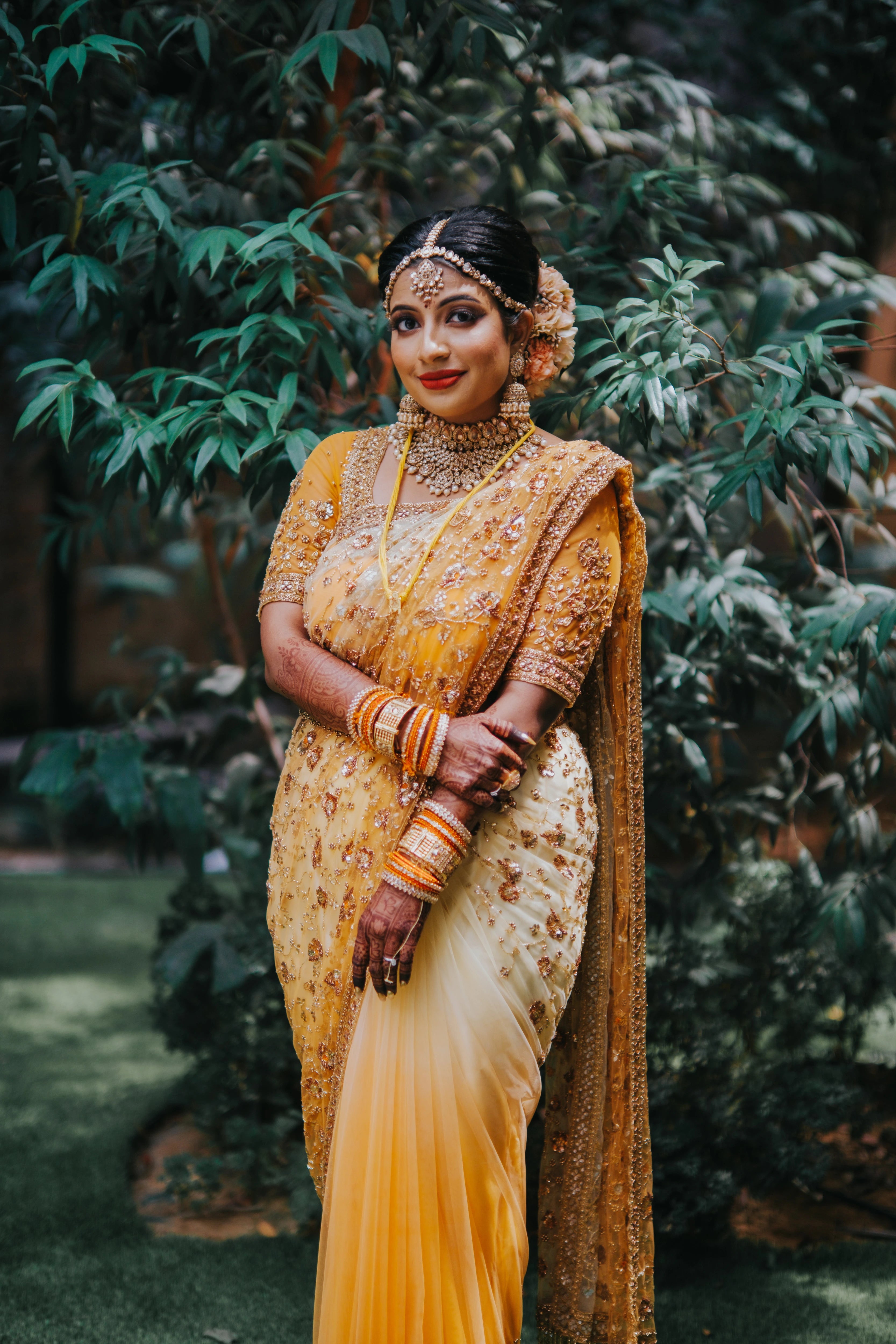 Bride Vishalini from Malaysia smiling in a mustard and ivory tulle saree, handcrafted by team Archana Karthick.