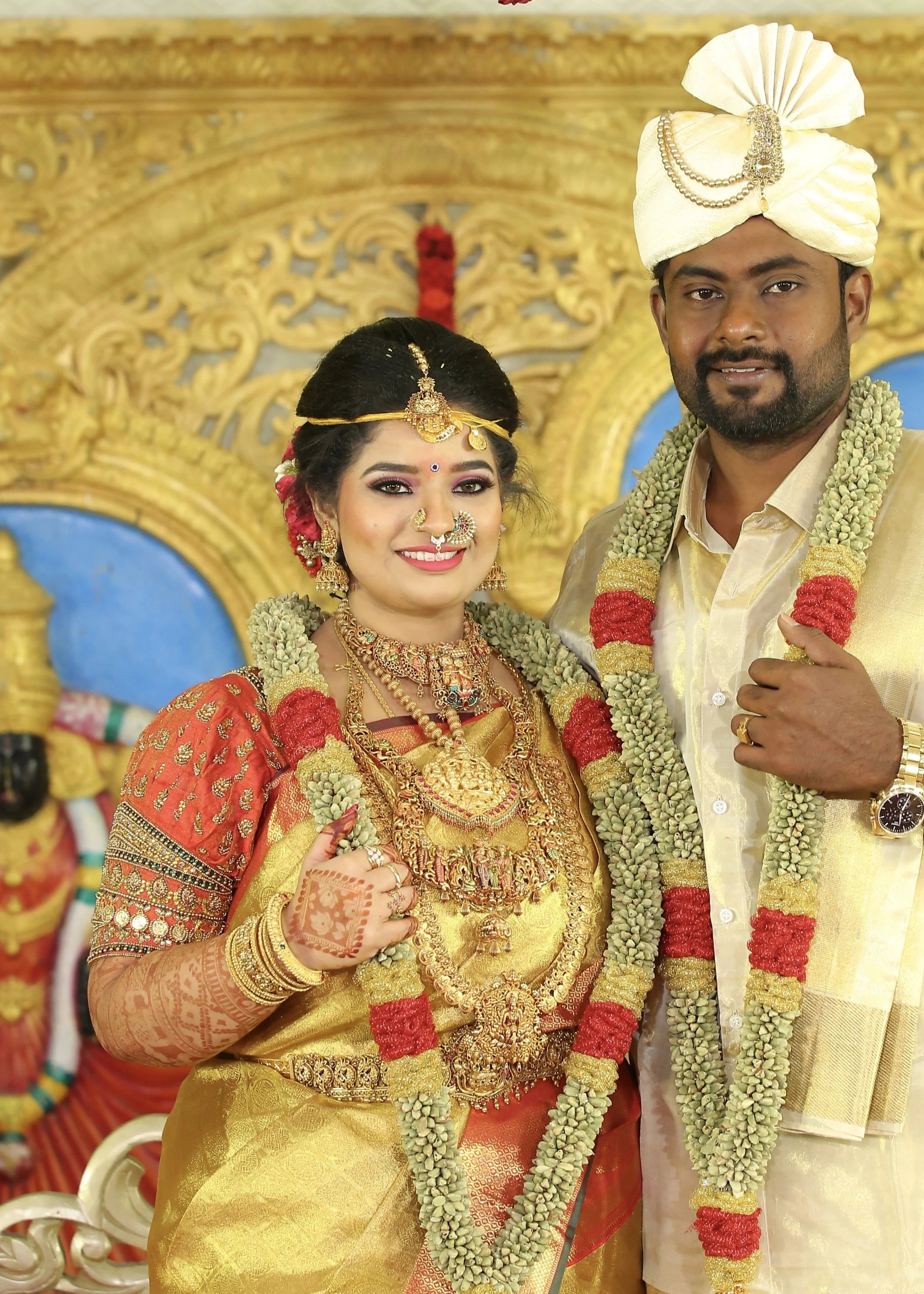 Bride Vishnulakshmi posing with groom in a concept burnt orange puff sleeved silk blouse, handcrafted with beads, zardozi, kundan, resham and stones by team Archana Karthick.