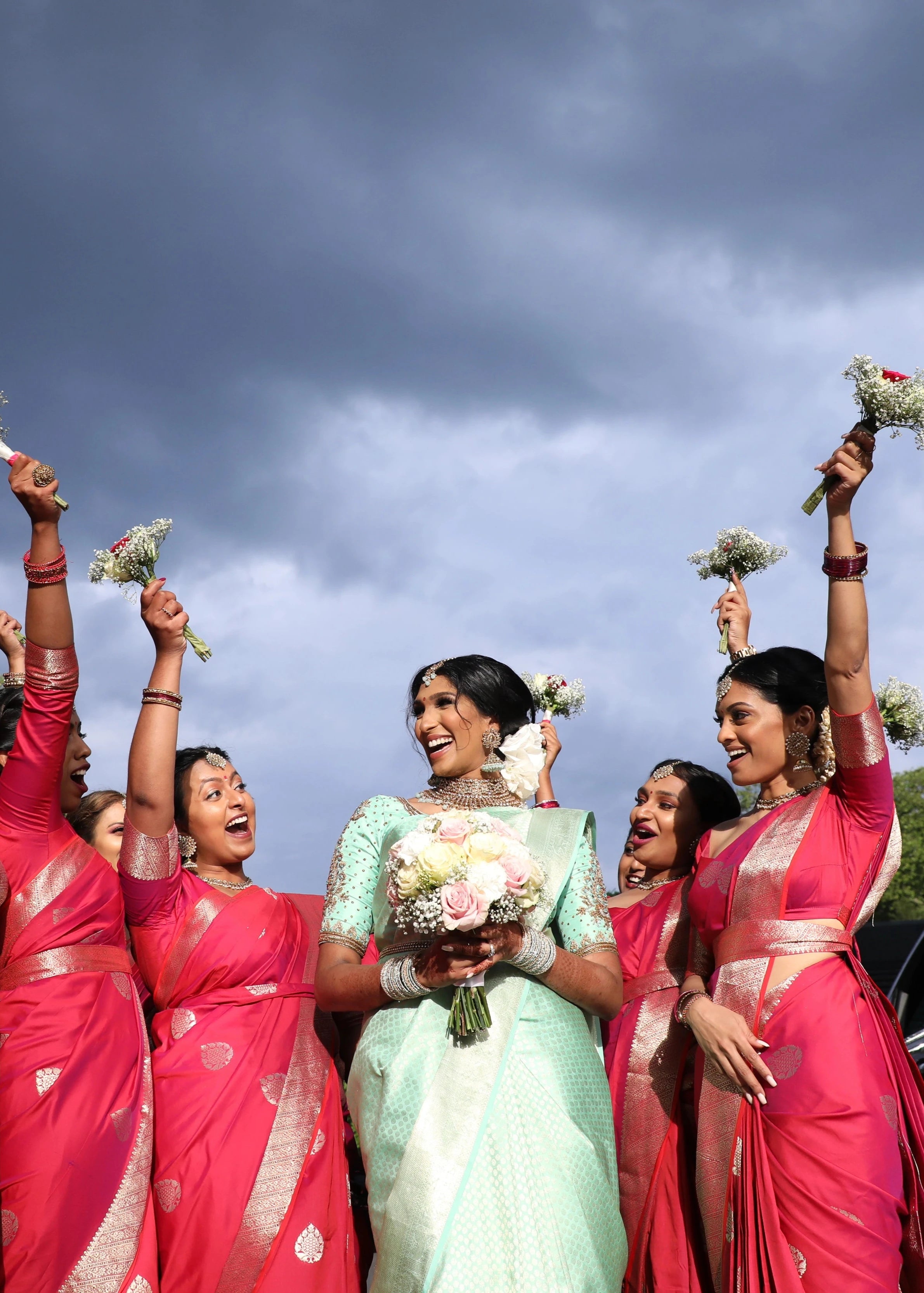 Bride Vithusika from Switzerland enjoying with bridesmaids in an aquamarine silk concept blouse for her engagement, handcrafted by team Archana Karthick.