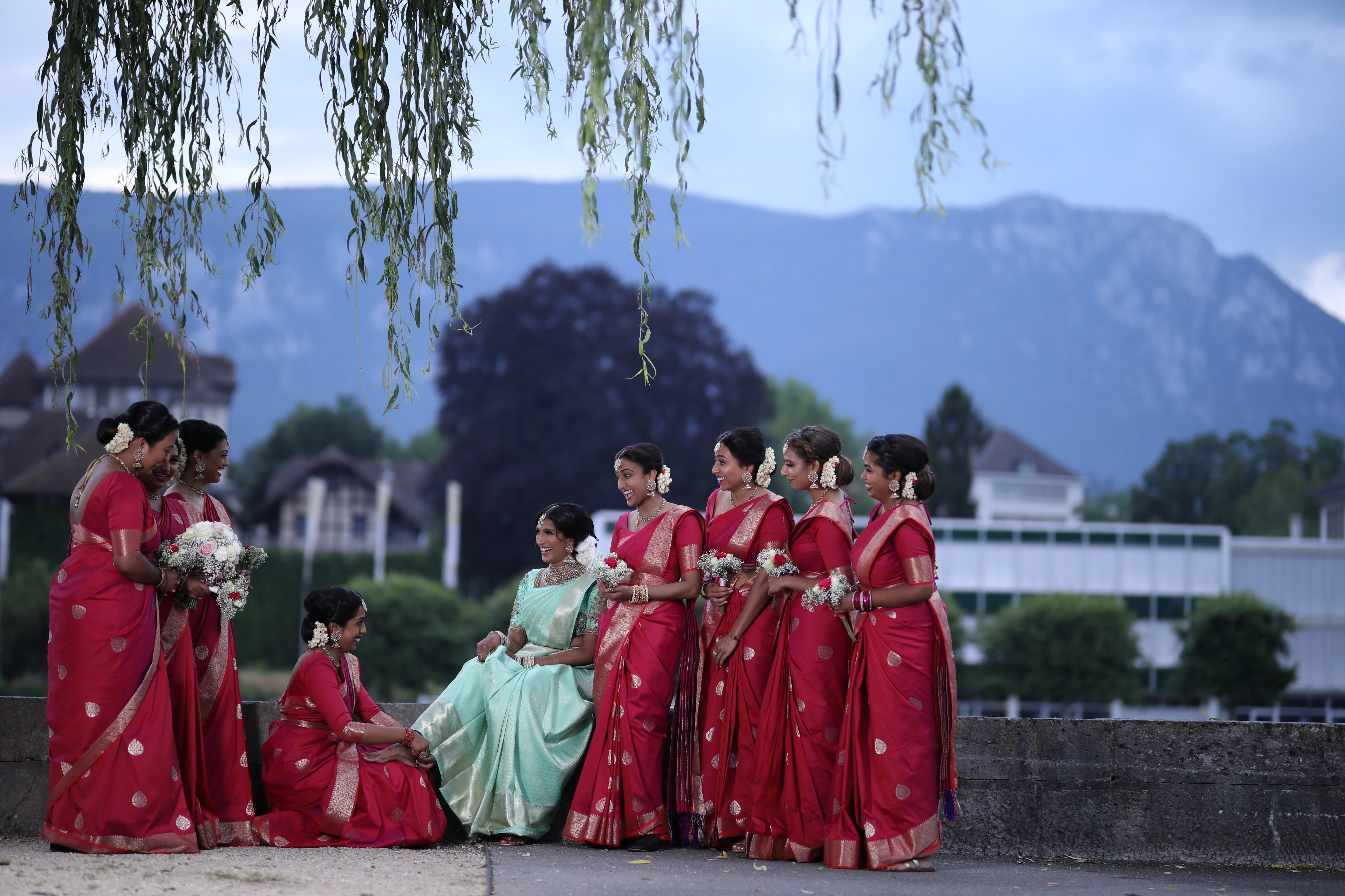 Bride Vithusika from Switzerland laughing with bridesmaids in an aquamarine silk concept blouse for her engagement, handcrafted by team Archana Karthick.