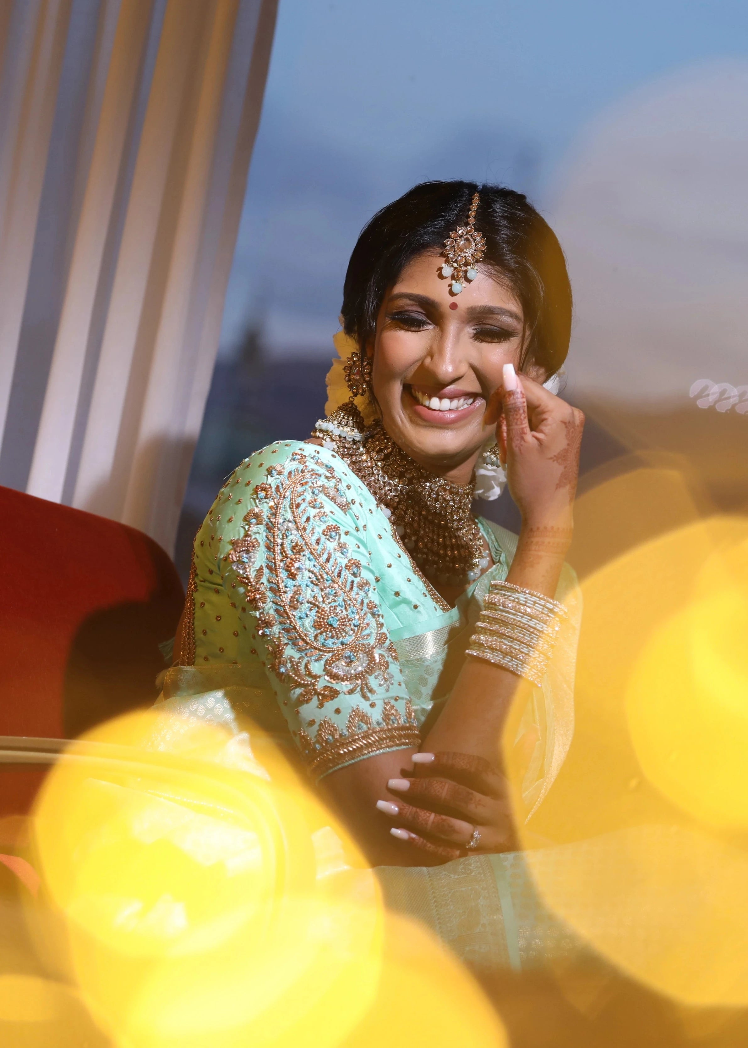 Bride Vithusika from Switzerland looking happy in an aquamarine silk concept blouse for her engagement, handcrafted by team Archana Karthick.