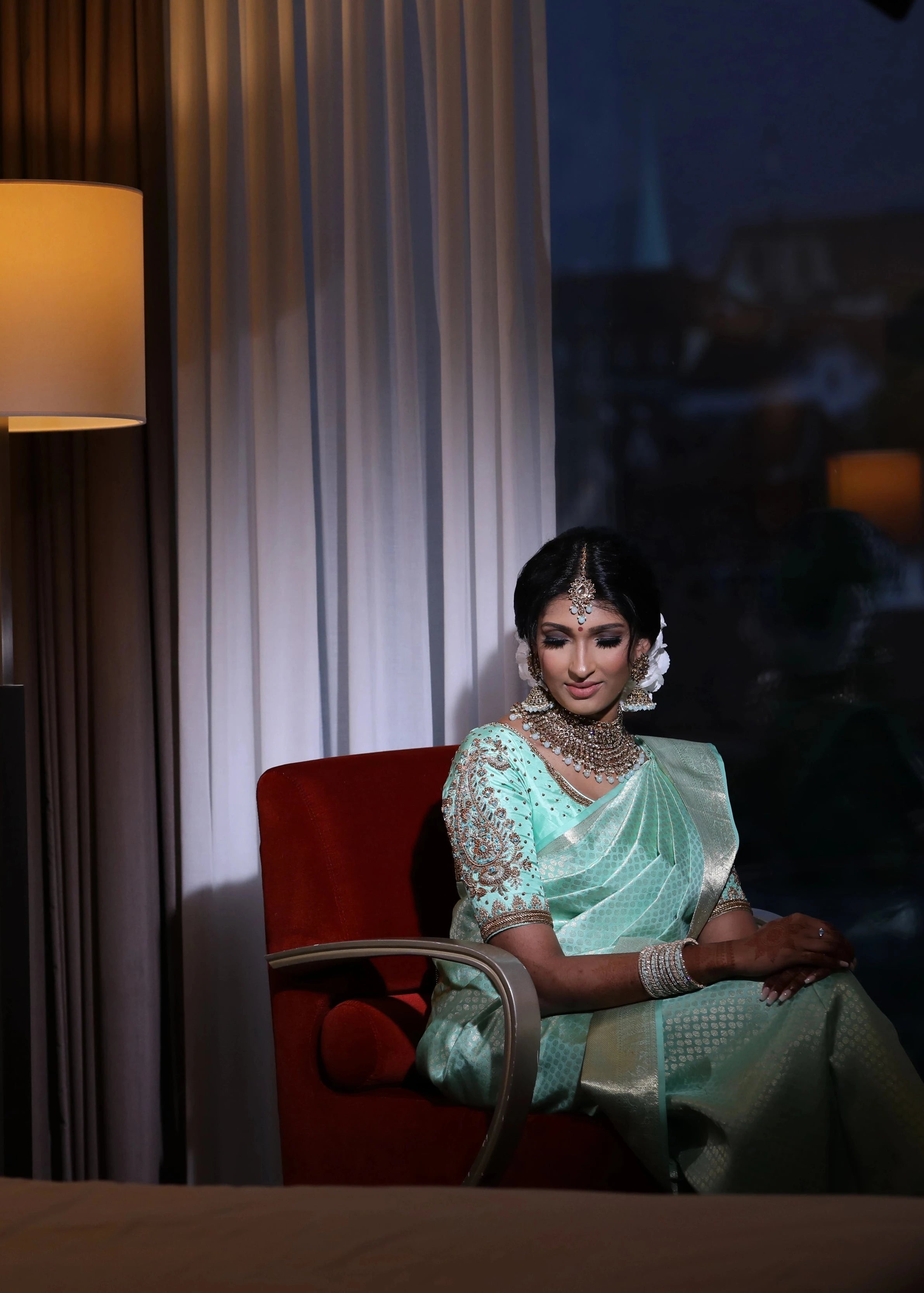 Bride Vithusika from Switzerland posing in an aquamarine silk concept blouse for her engagement, handcrafted by team Archana Karthick.