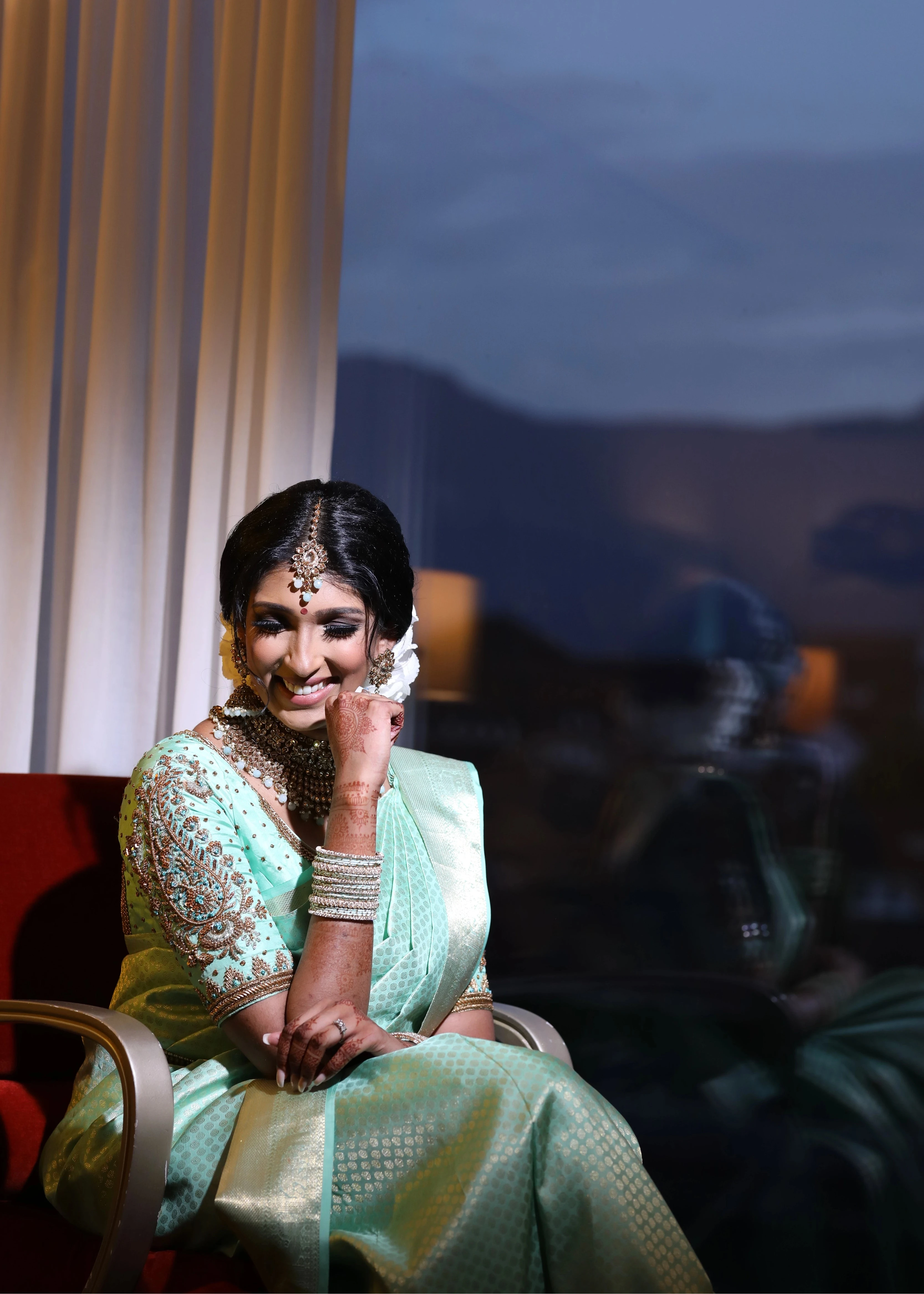Bride Vithusika from Switzerland smiling in an aquamarine silk concept blouse for her engagement, handcrafted by team Archana Karthick.