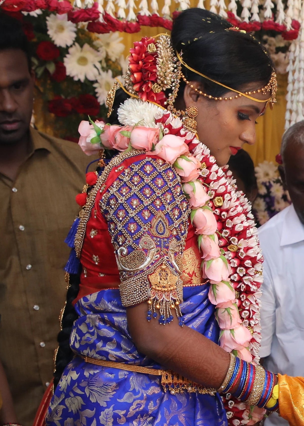 Bride during her ritual in a concept peacock blouse in blue and red silk, handcrafted with zardozi, beads, resham knot work and goddess pendant on sleeves.