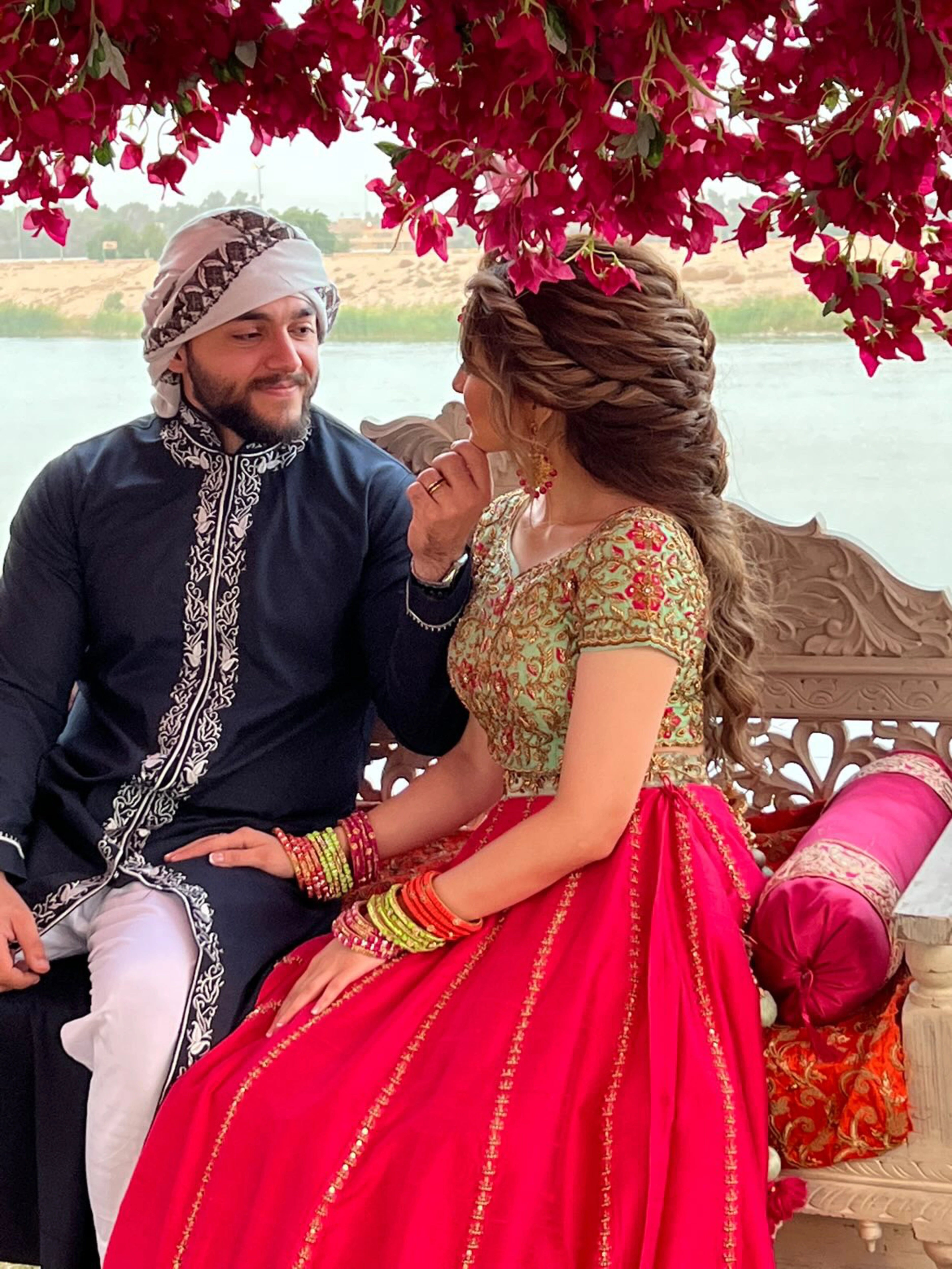 Bride from Baghdad, Iraq posing with groom in a hot pink and mint green raw silk lehenga, handcrafted by team Archana Karthick.