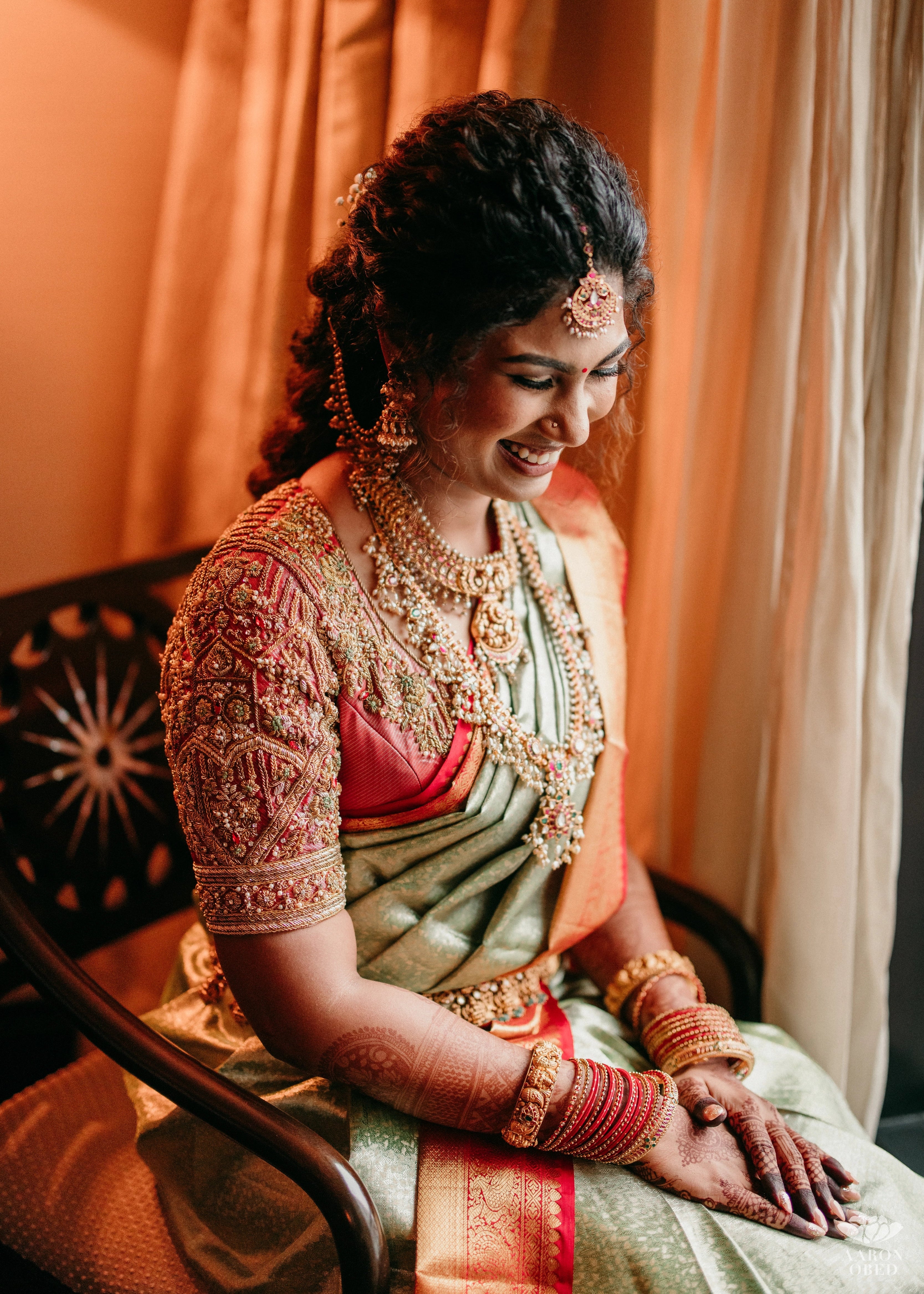 Bride from Chennai laughing in a concept red silk blouse handcrafted intricately with rhinestones, pearls, zardozi, resham knot work and stones. Designed by Archana Karthick