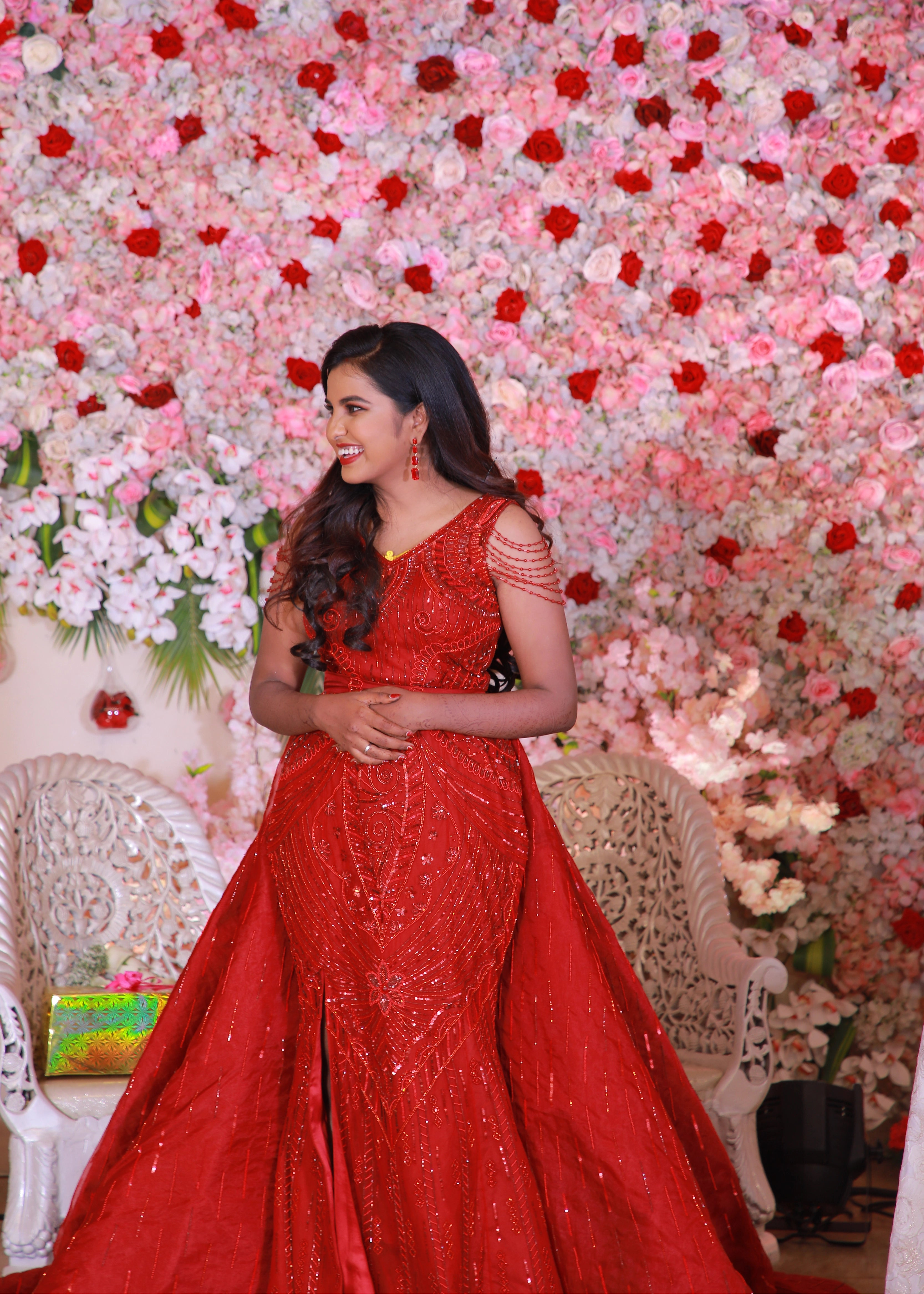 Bride from Chennai laughing in a red mermaid gown with detachable trail handcrafted with rhinestones, crystal beads, cutdanas and sequins. Designed by Archana Karthick