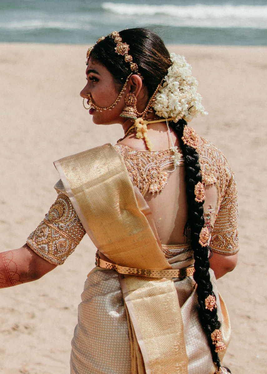 Bride from Chennai posing at beach in a concept blouse in gold silk handcrafted intricately with zardozi, crystal beads, stones, pearls and beads. Designed by Archana Karthick.