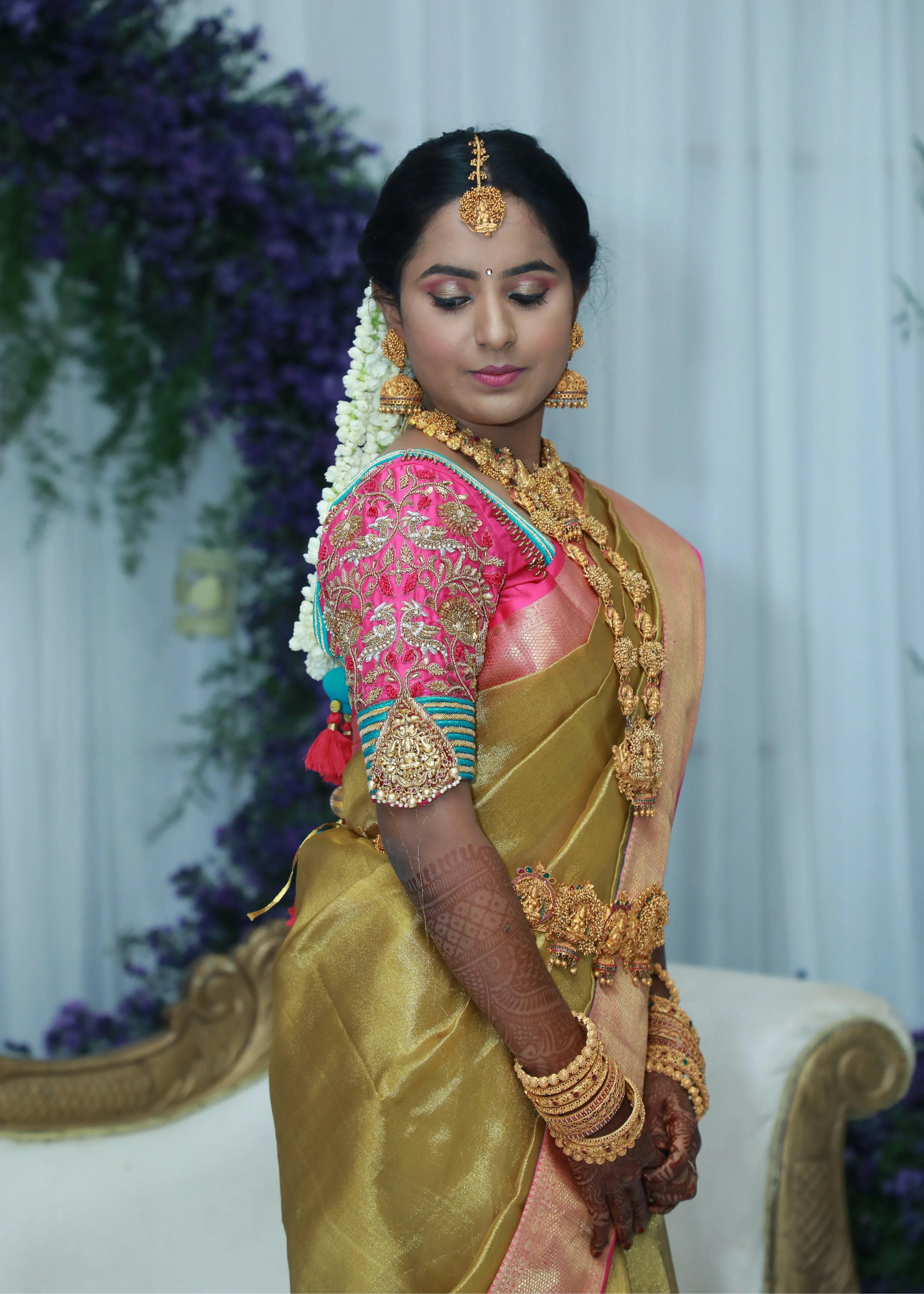 Bride from Chennai posing for side profile in pink silk blouse with zardozi, kundan, resham knot work and kundan embellishments. Designed by Archana Karthick