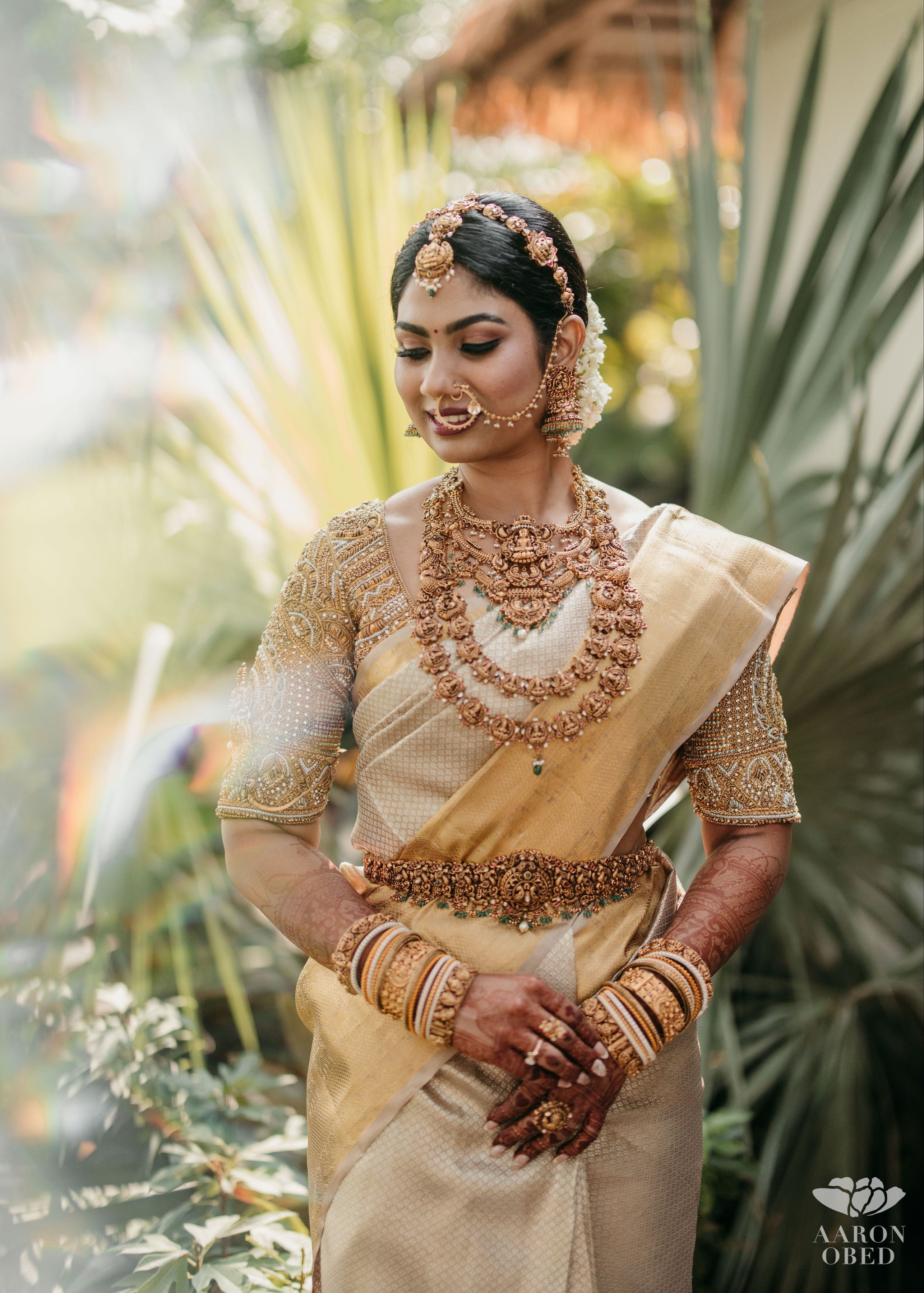 Bride from Chennai posing in a concept blouse in gold silk handcrafted intricately with zardozi, crystal beads, stones, pearls and beads. Designed by Archana Karthick.